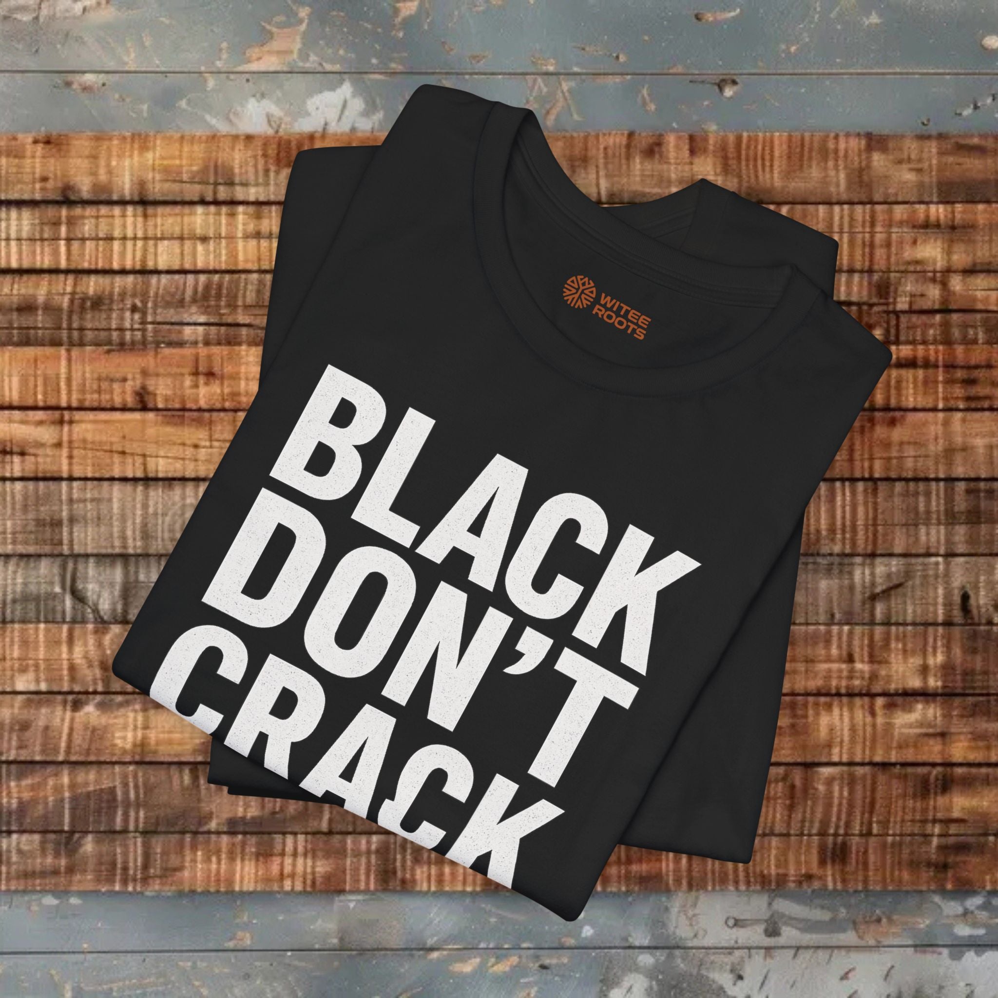 Black t-shirt with text folded Ed on a wooden surface.
