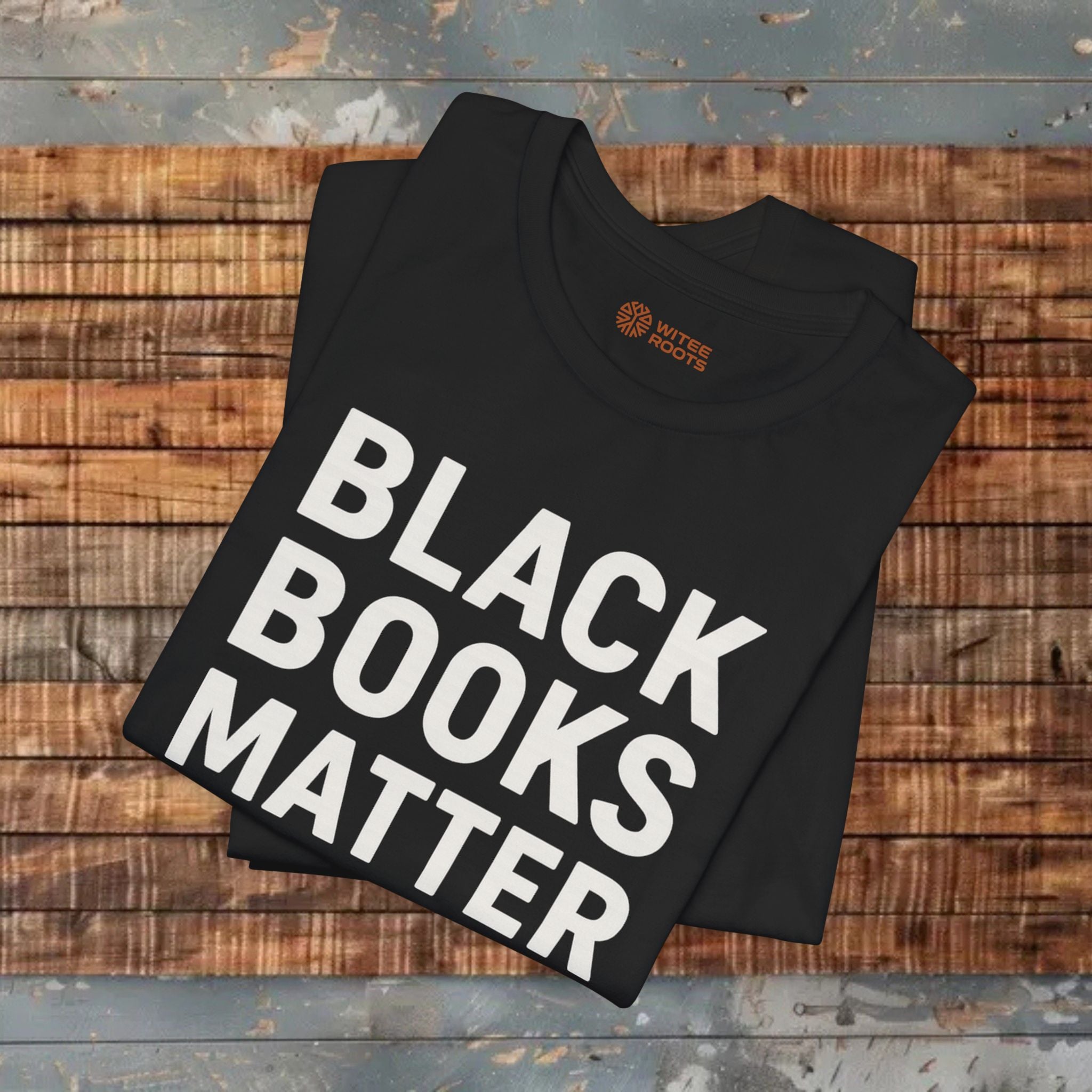 Black t-shirt with 'BLACK BOOKS MATTER' text on a wooden surface