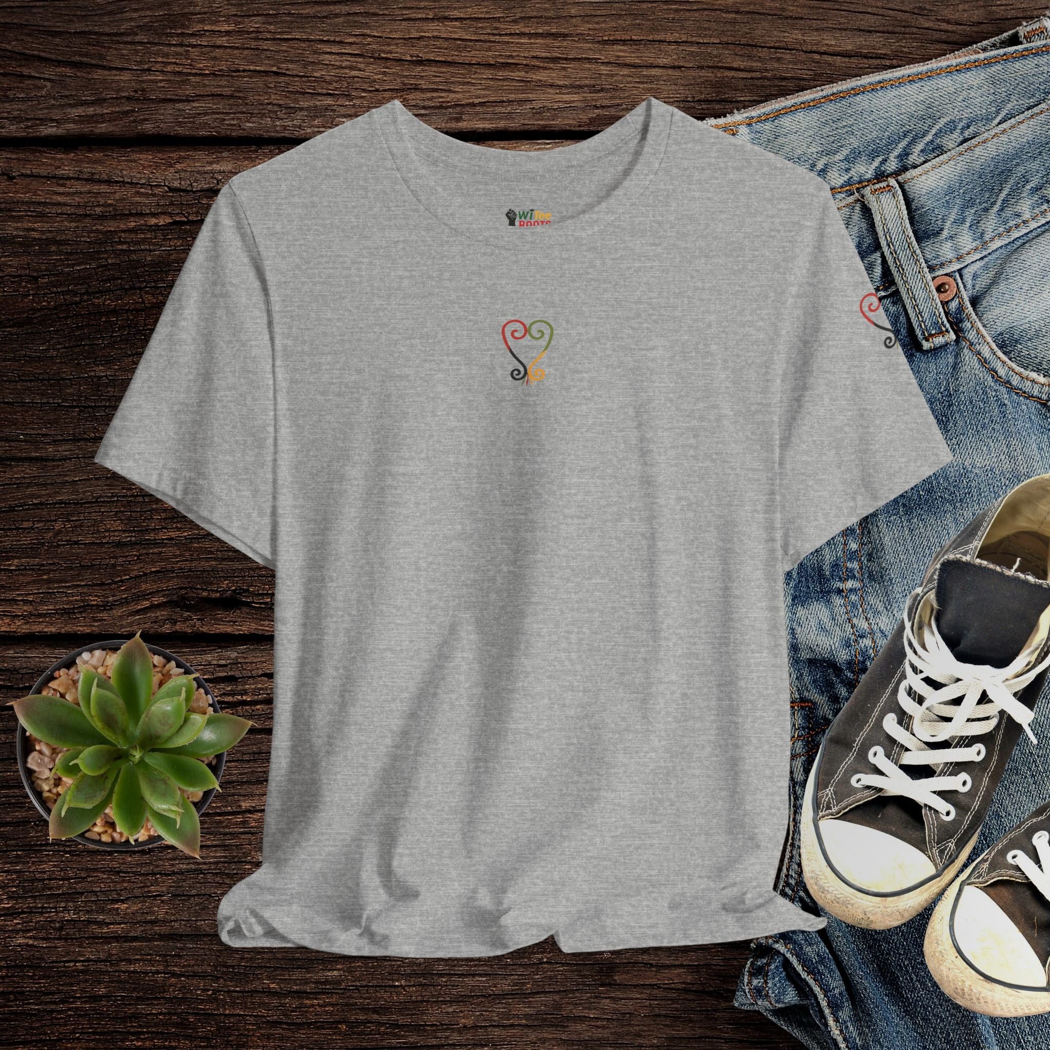 Gray t-shirt with a colorful design on a wooden surface with jeans and sneakers.