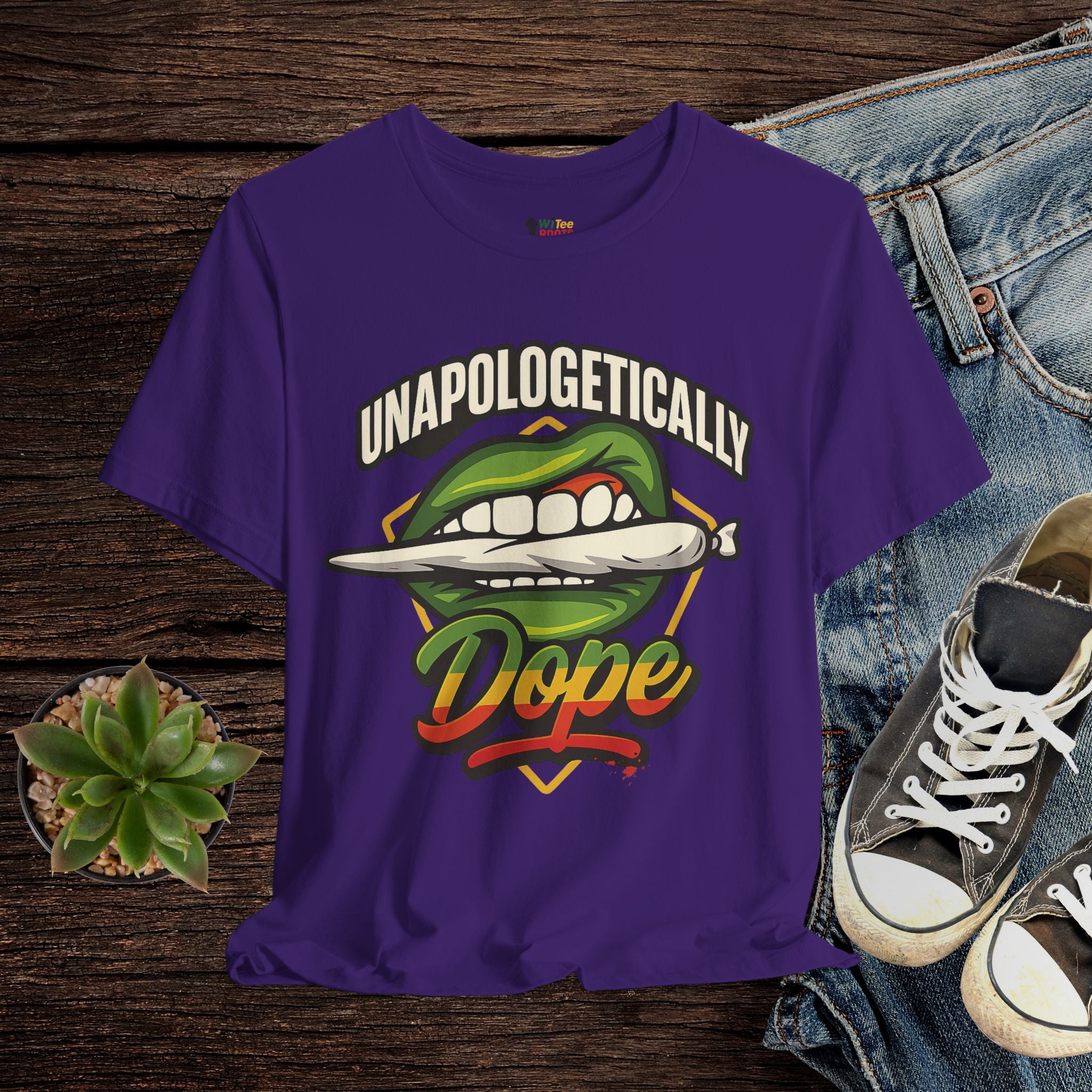 Purple t-shirt with graphic design and text on a wooden surface with jeans and sneakers.