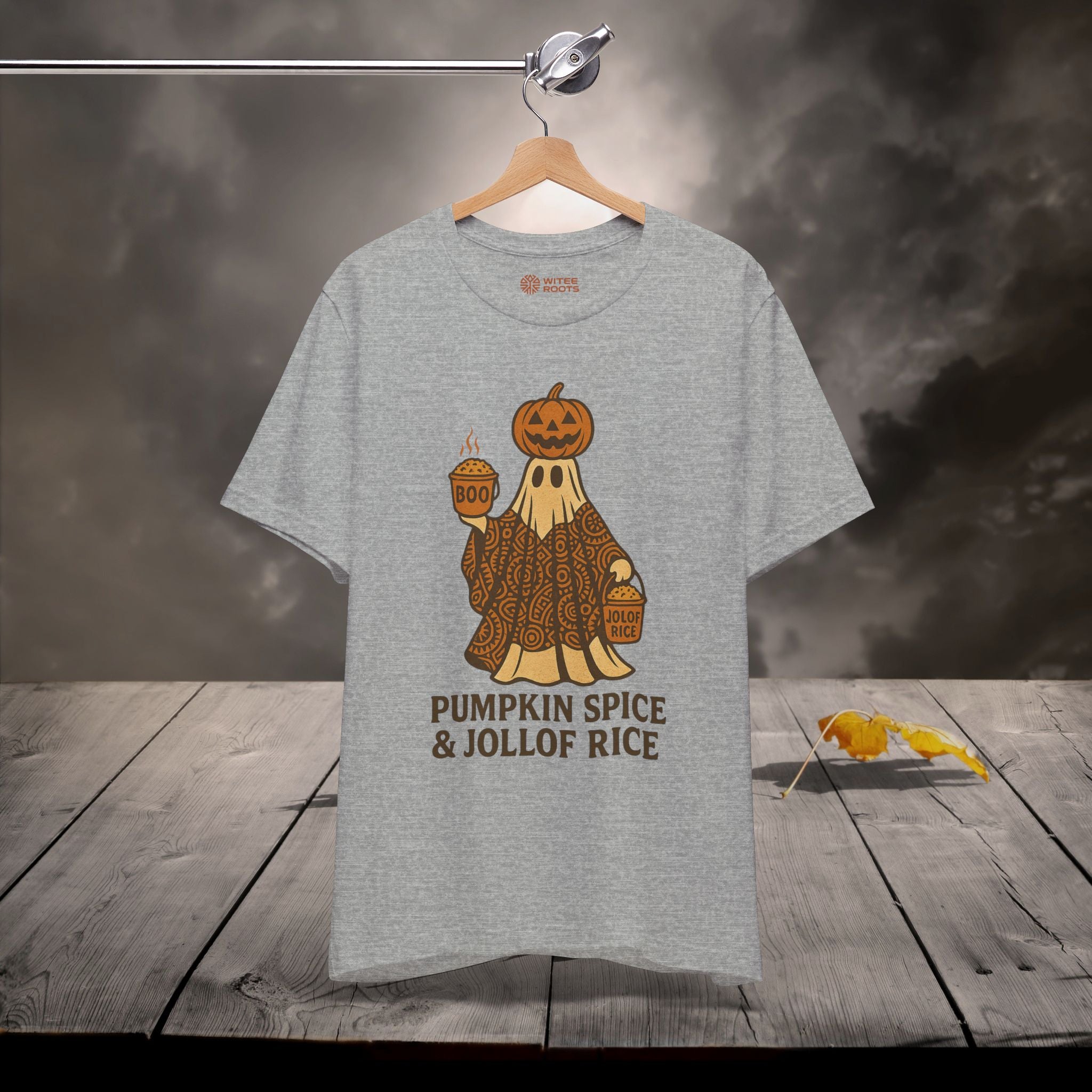 Gray t-shirt with a pumpkin spice and jollof rice graphic on a wooden surface.