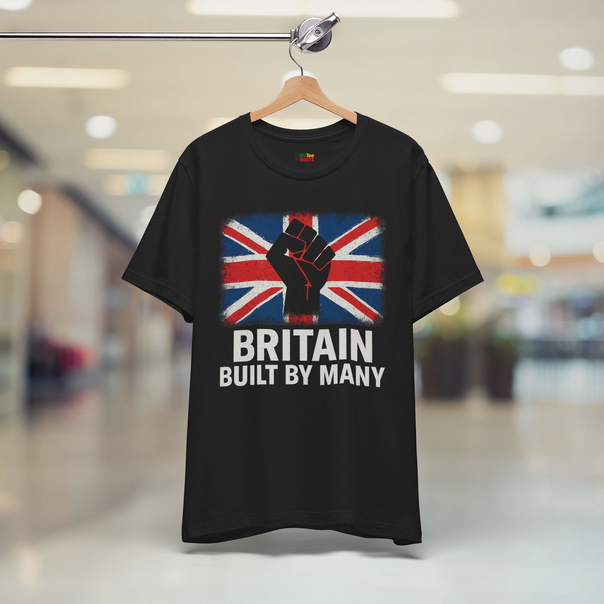 Black t-shirt with Union Jack design and text on a hanger in a store setting