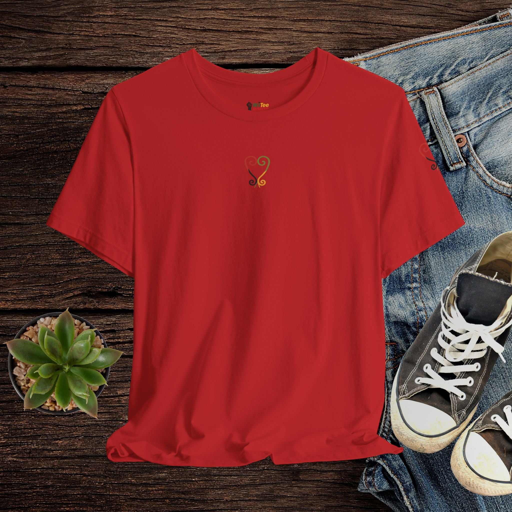 Red t-shirt with a small logo on a wooden surface with jeans and sneakers.