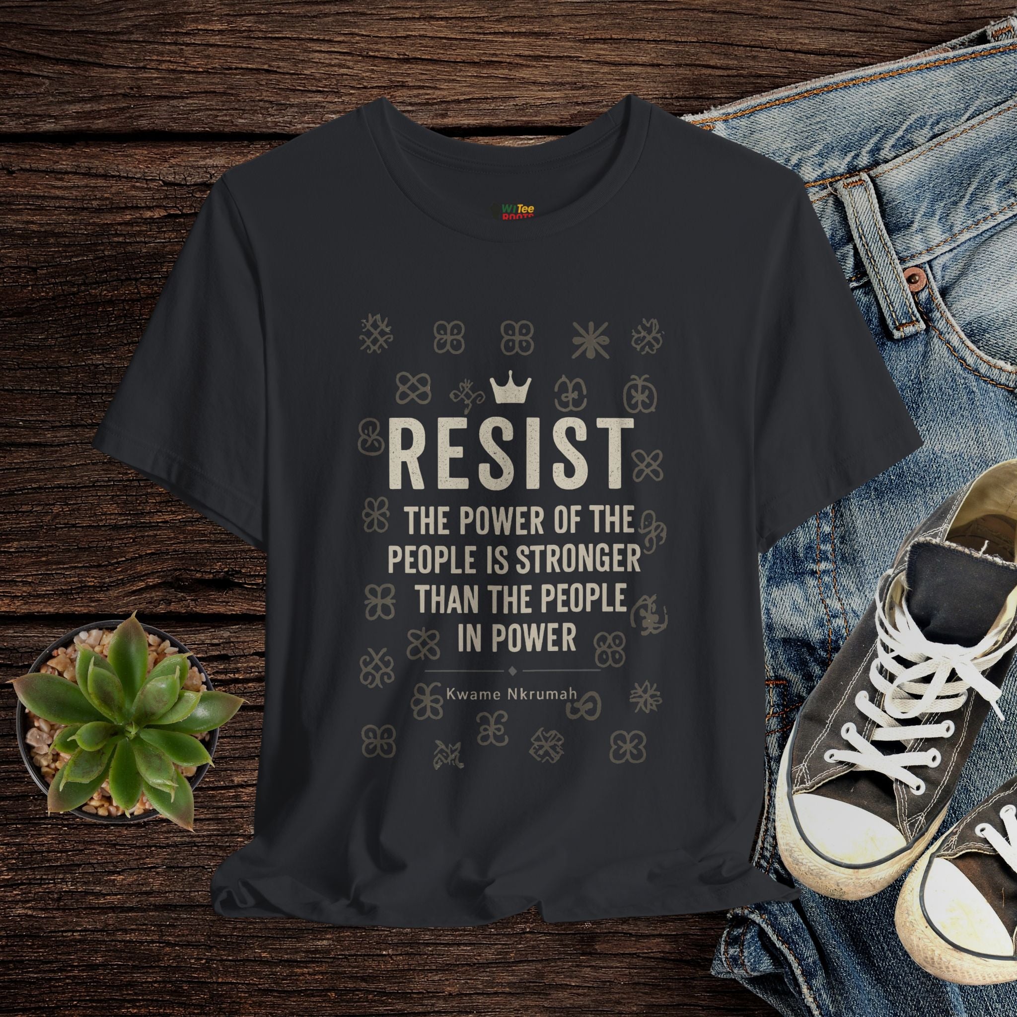 Black t-shirt with motivational quote on a wooden surface with jeans and sneakers.