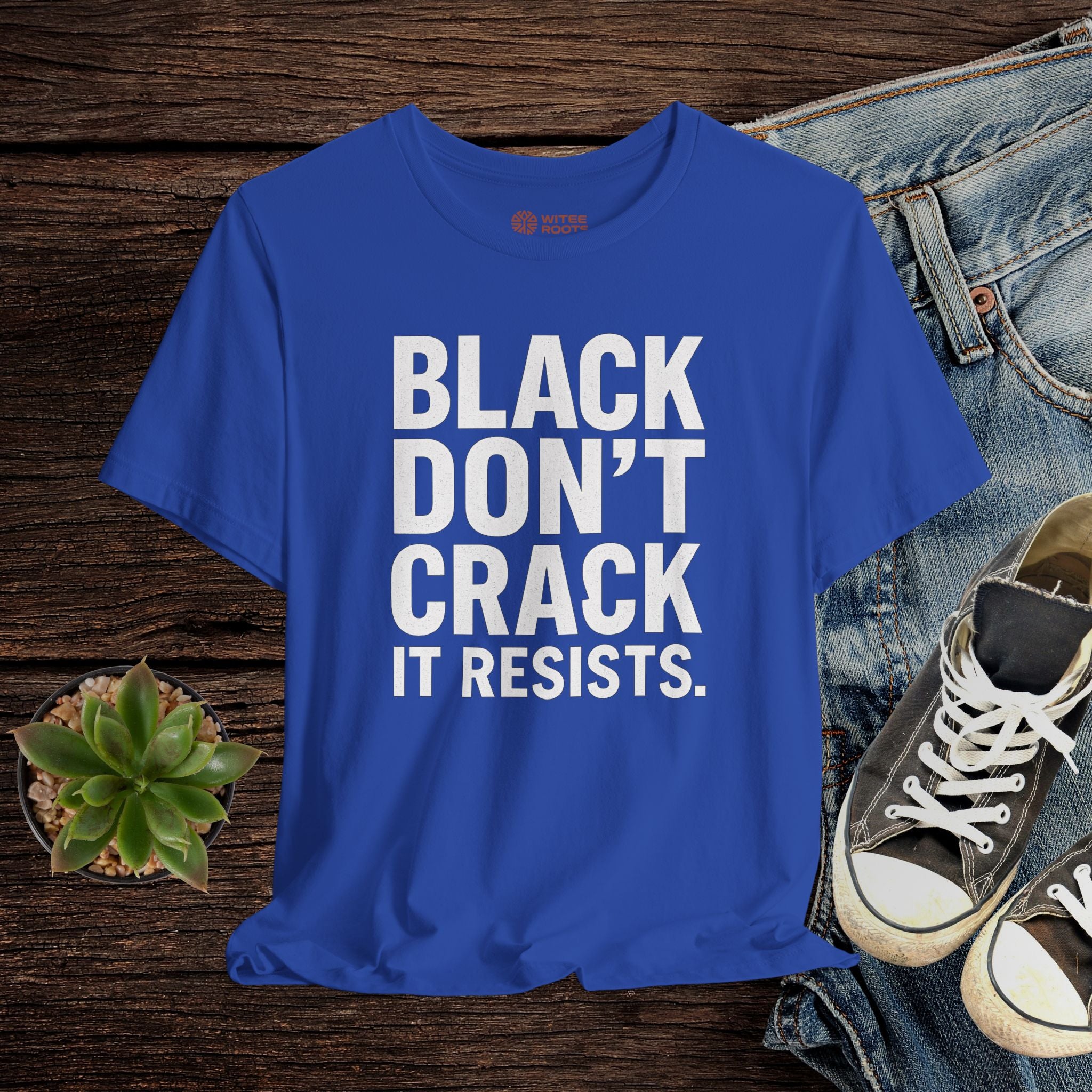 Blue t-shirt with text on a wooden surface with jeans and sneakers.