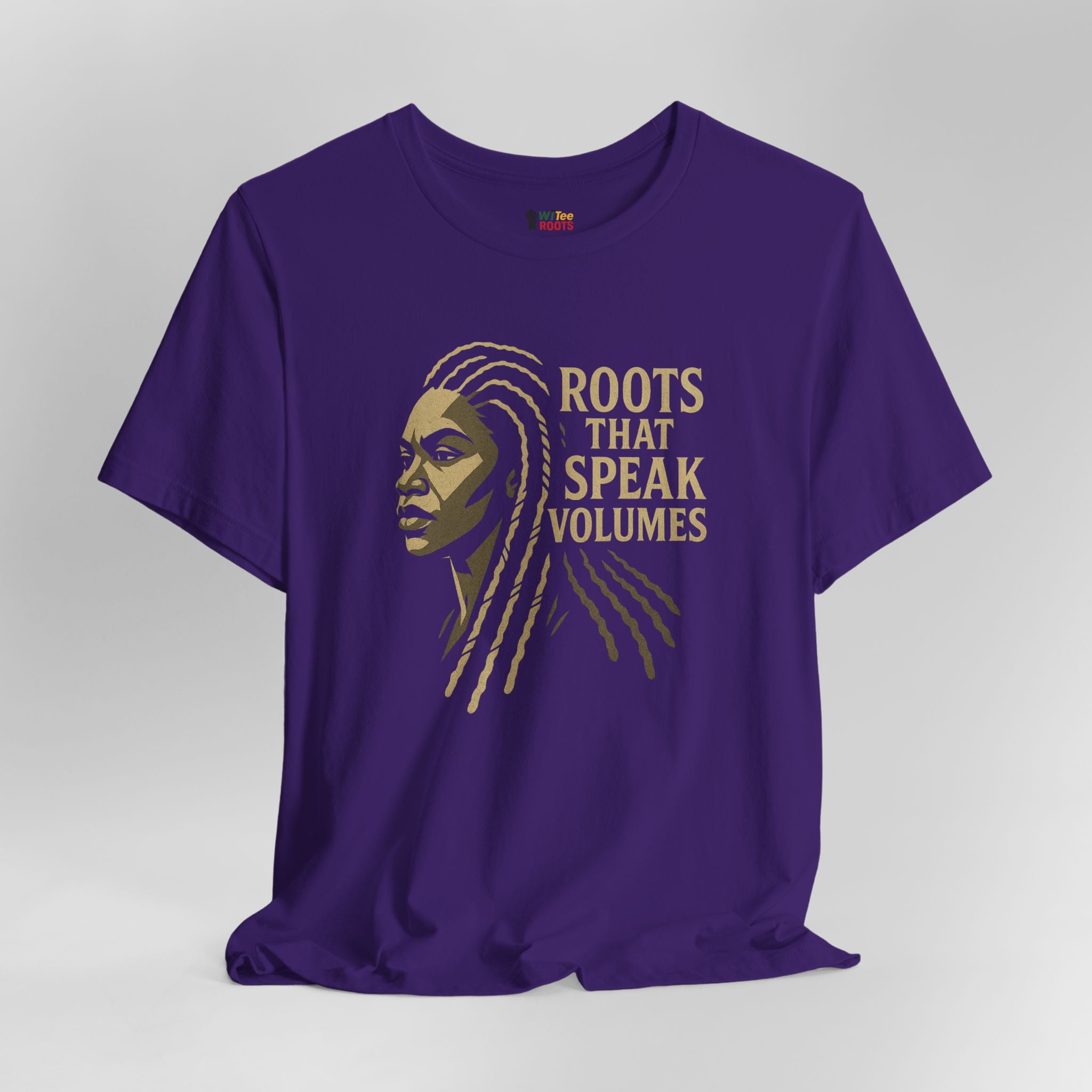 Purple t-shirt with a graphic of a woman's face and 'Roots That Speak Volumes' text on a gray background