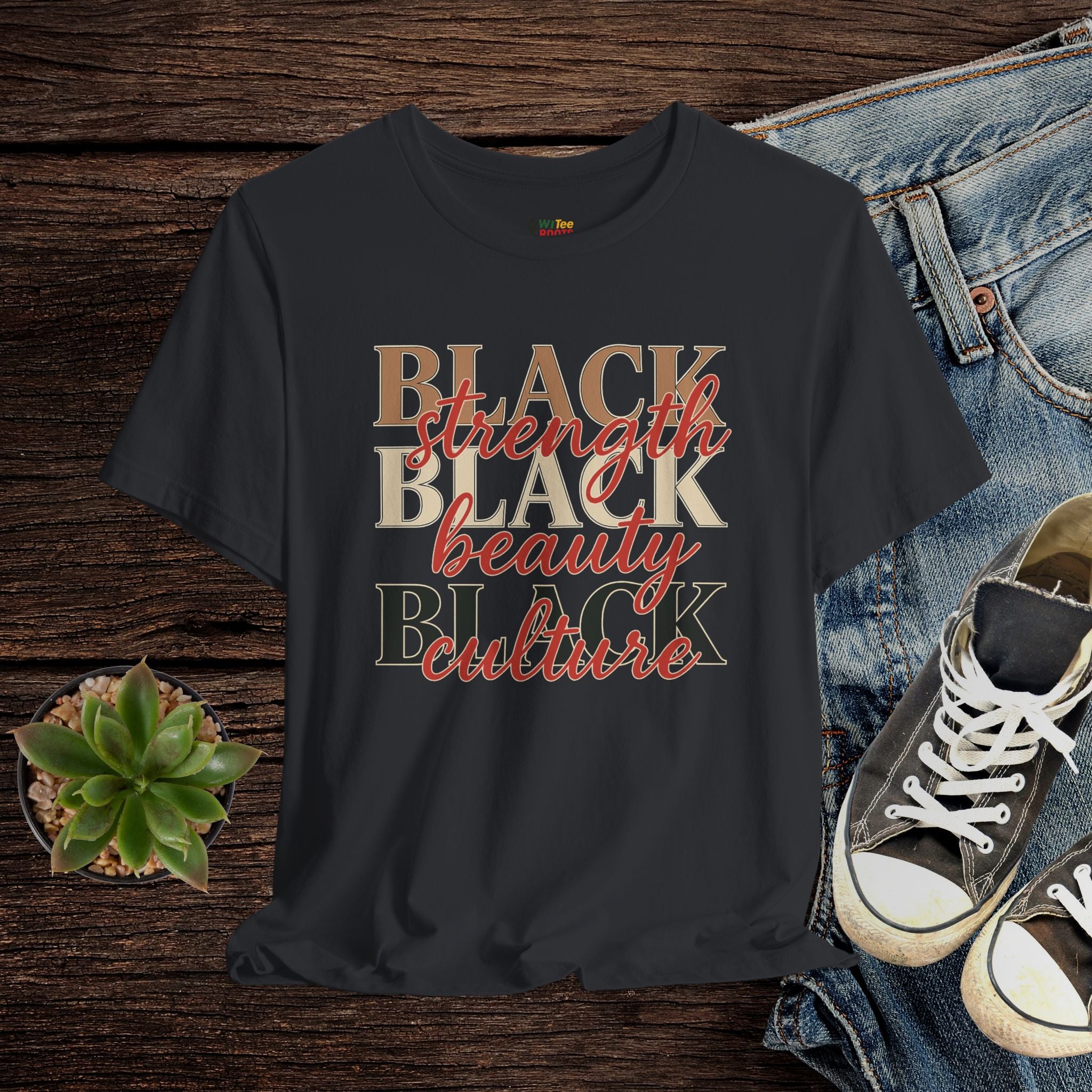 Black t-shirt with 'BLACK strength BLACK beauty BLACK culture' text on a wooden surface with jeans and sneakers.