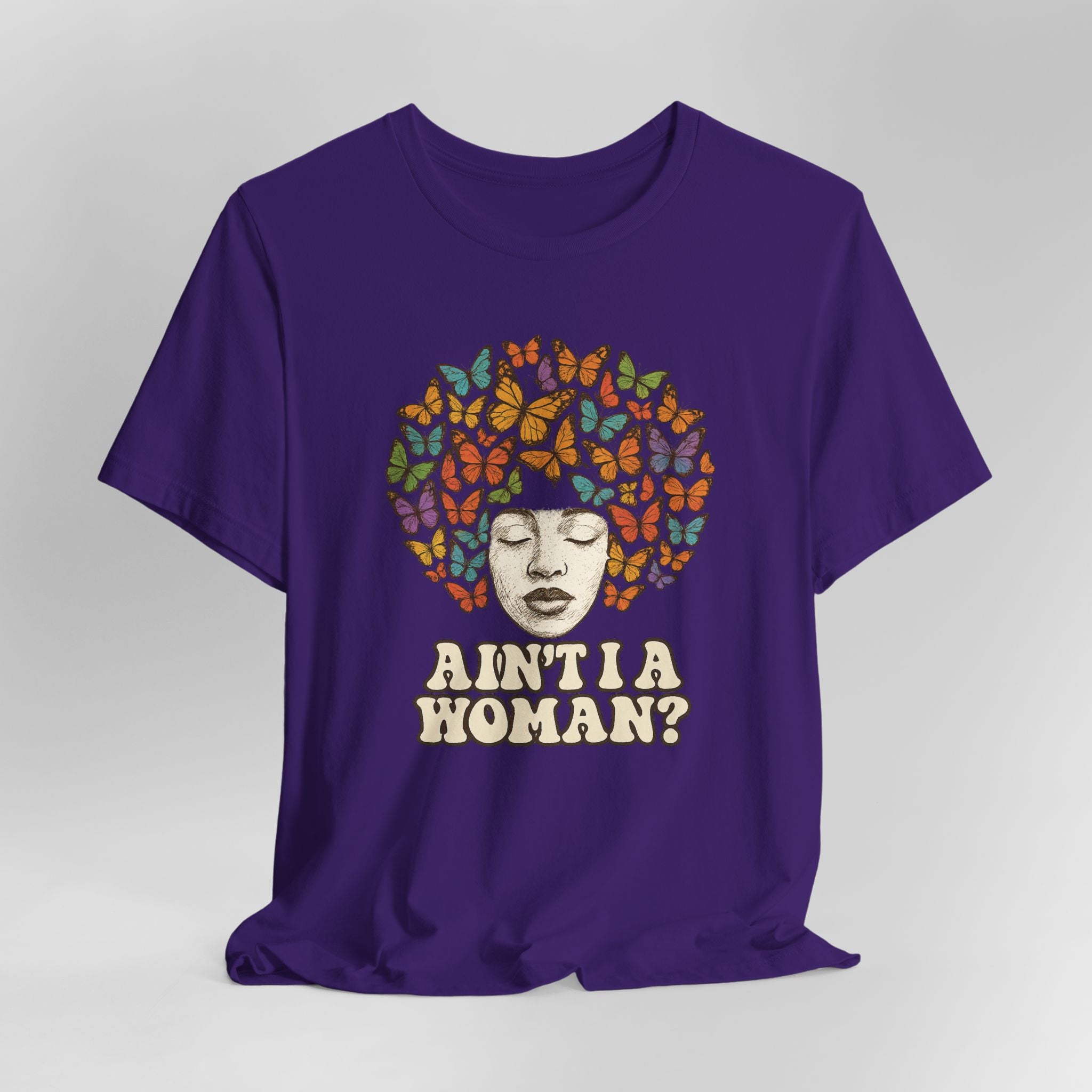 Purple t-shirt with a graphic of a woman's face with butterflies and 'Ain't I a Woman?' text on a gray background