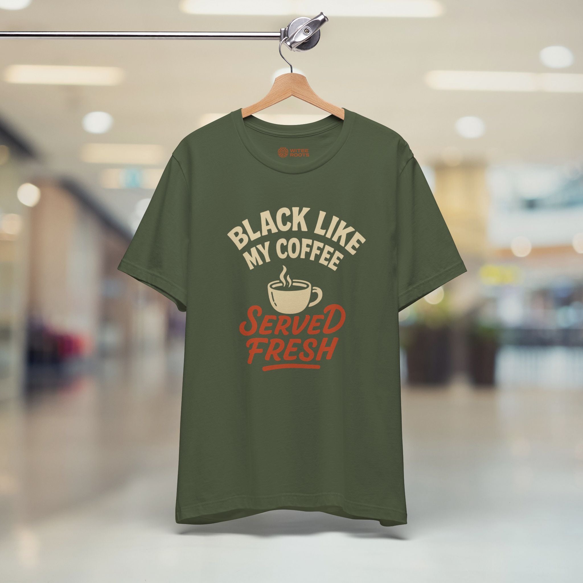 Green t-shirt with text and coffee graphic on a hanger in a store setting