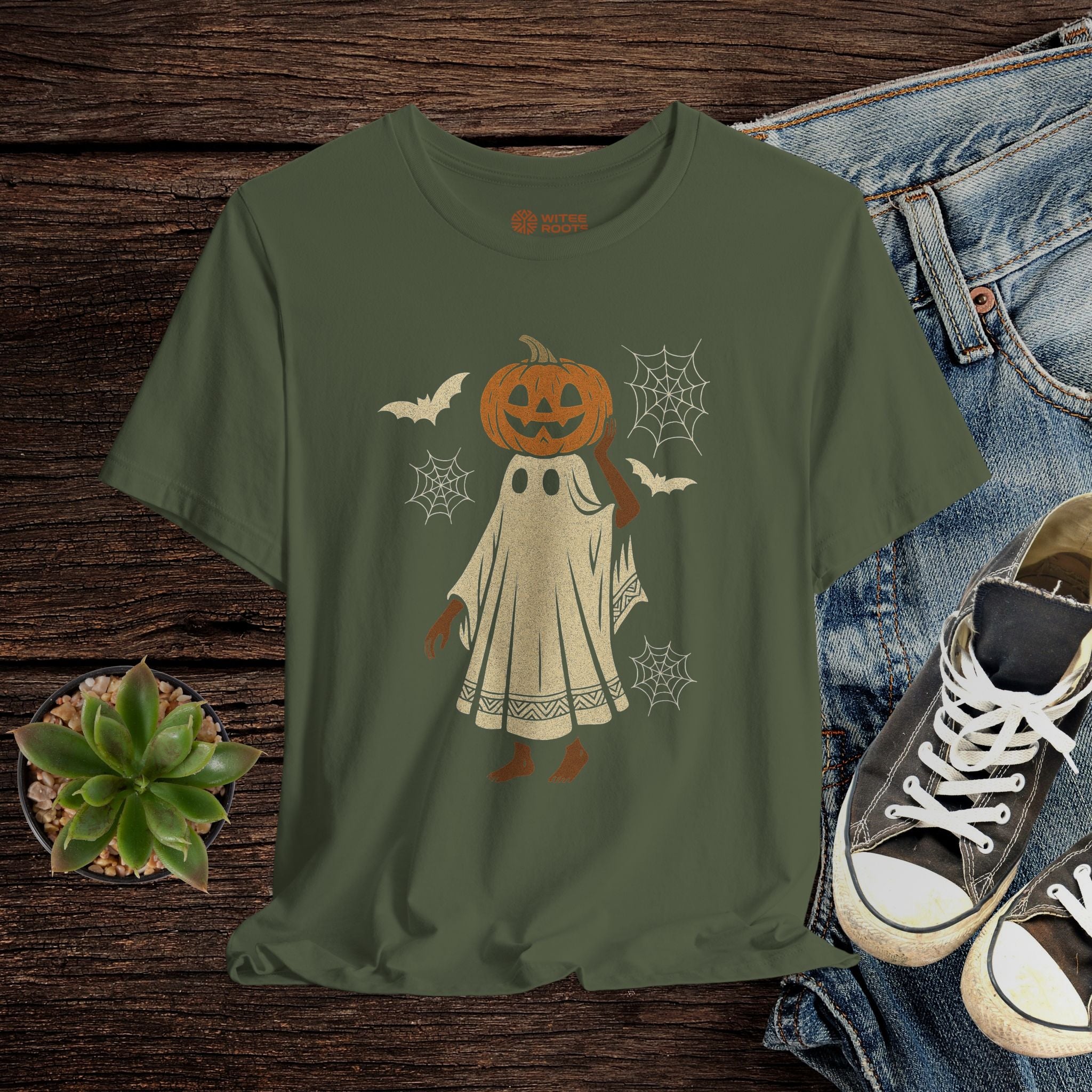 Green t-shirt with Halloween-themed design on a wooden surface with jeans and shoes.