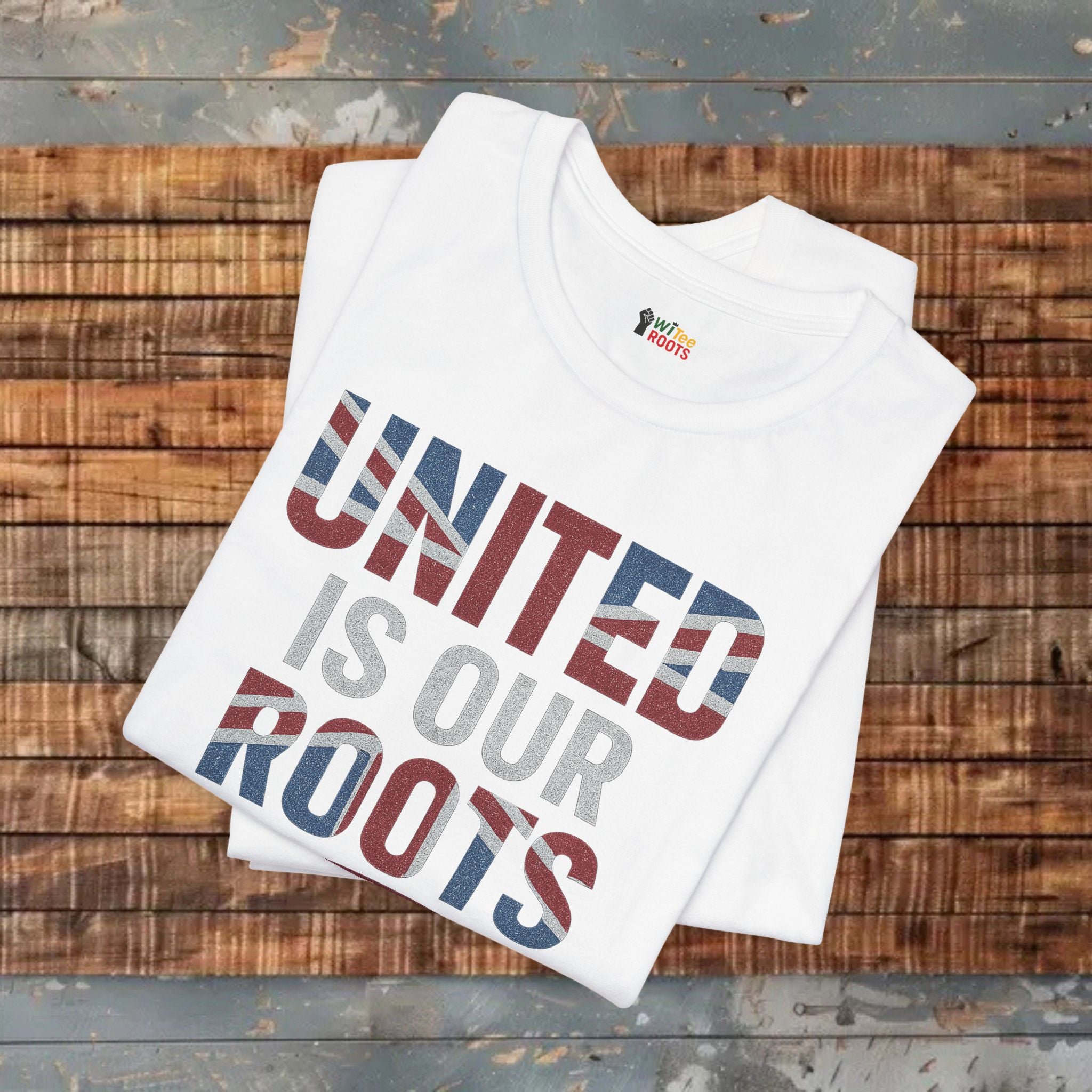 White t-shirt with 'UNITED IS OUR ROOTS' text on a wooden surface