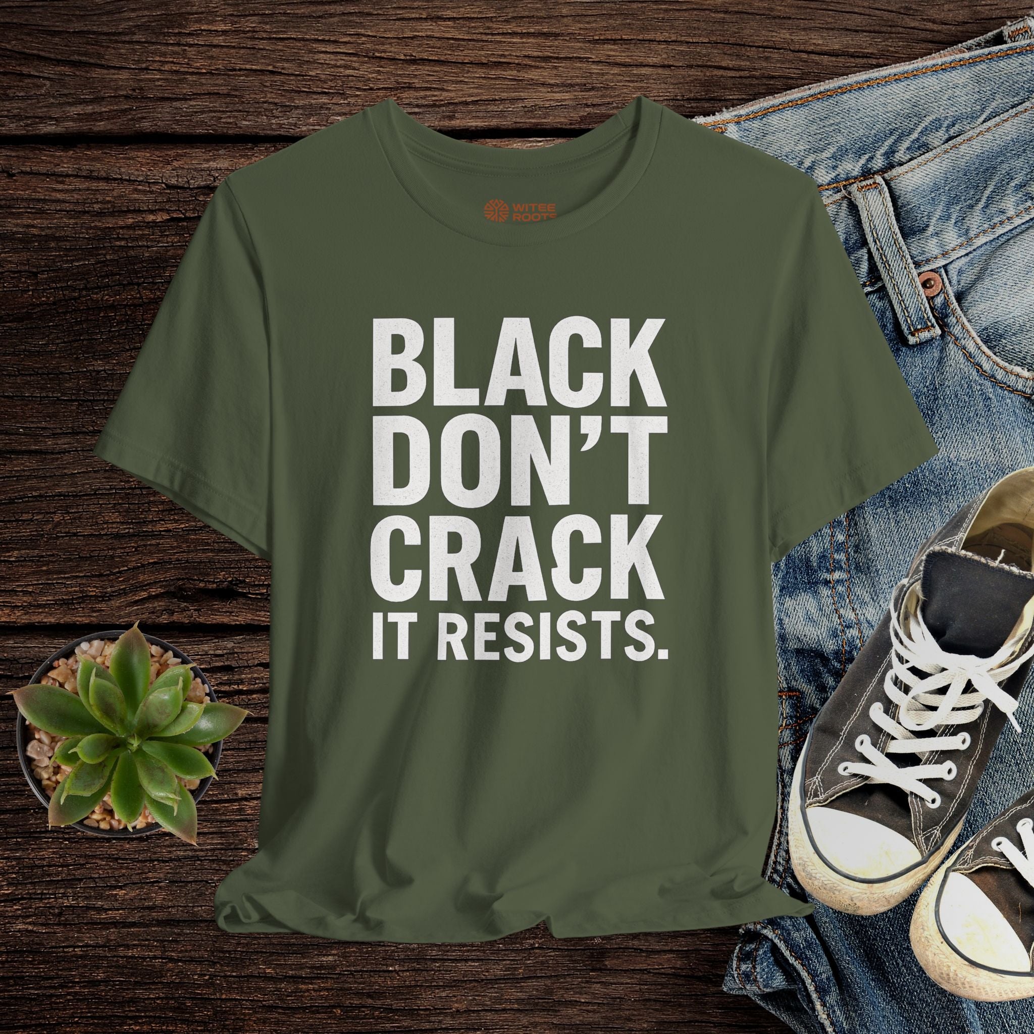 Green t-shirt with text on a wooden surface with jeans and sneakers.