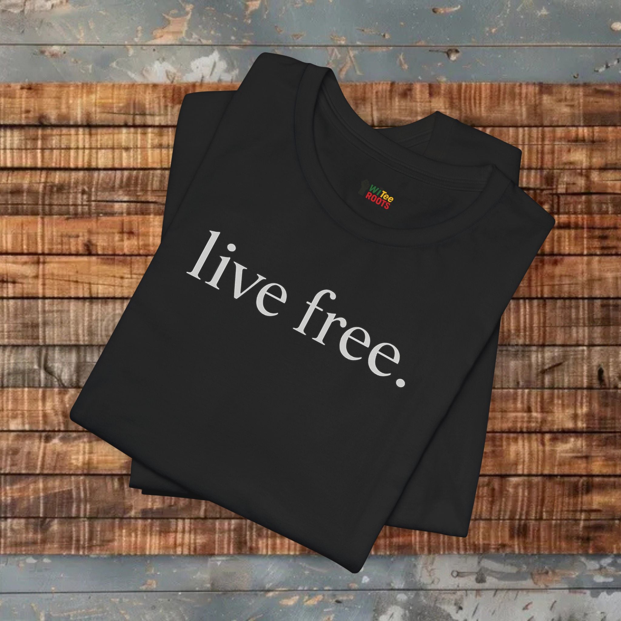 Black ts-hirt with 'live free' printed on it, folded on a wooden surface