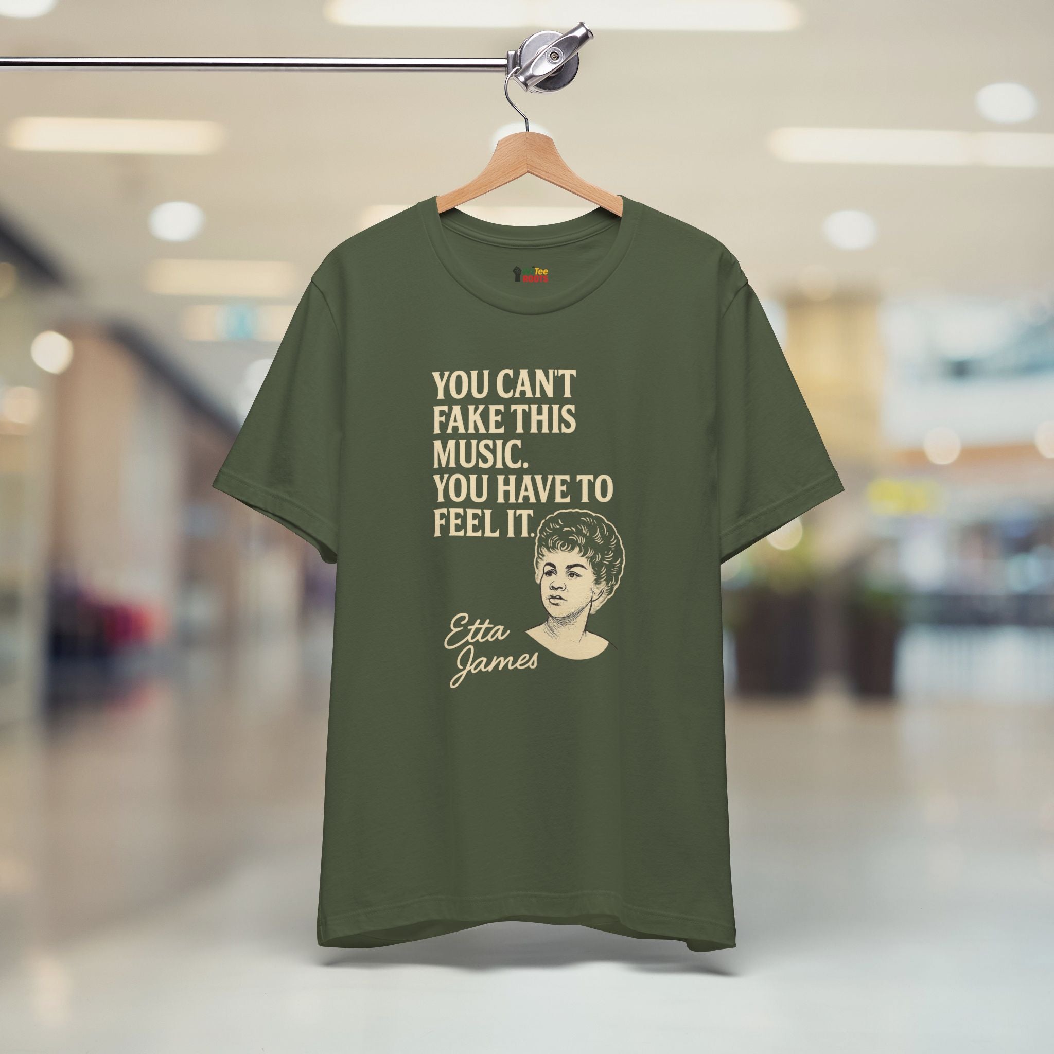 Green t-shirt with text and a portrait on a hanger in a store setting