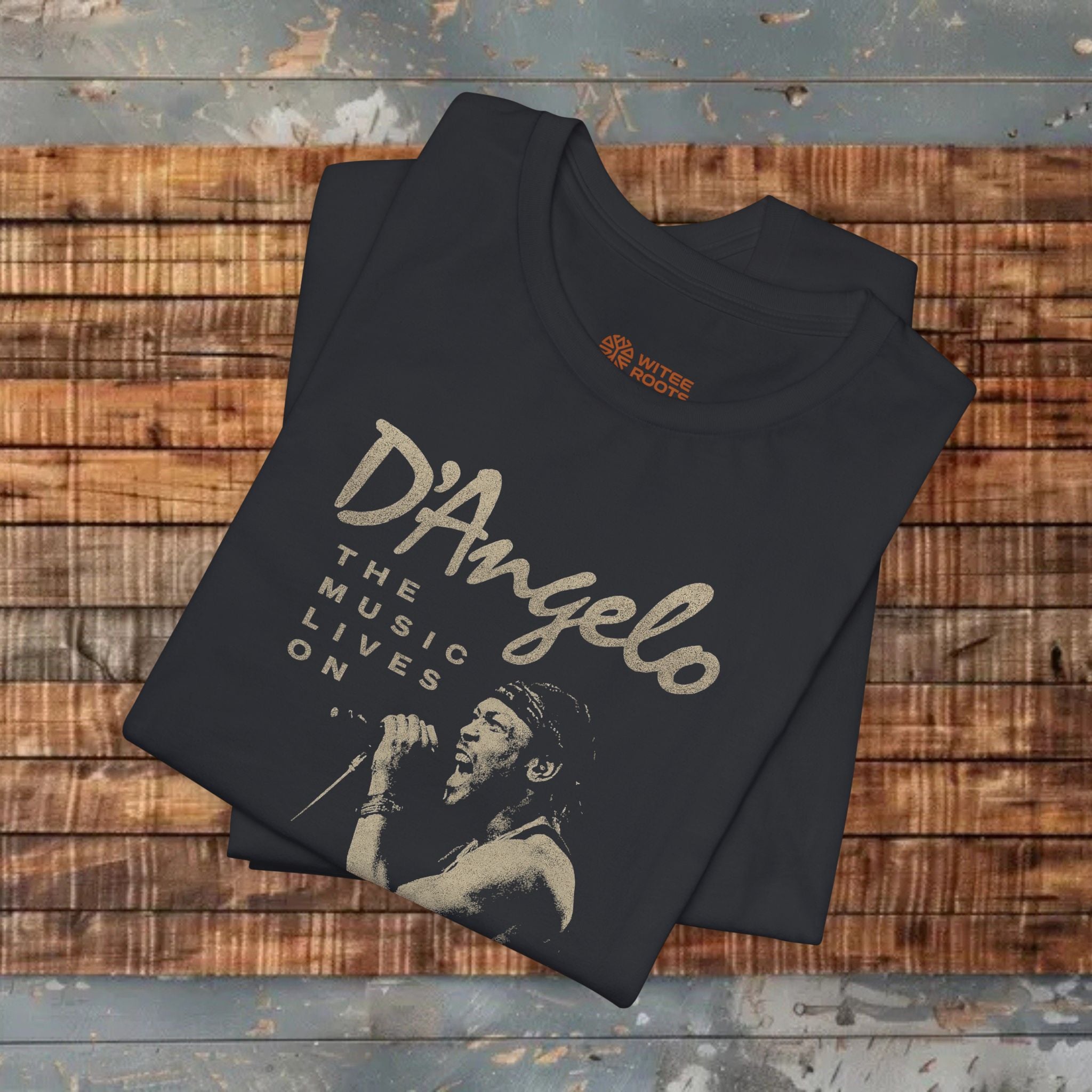 Folded black t-shirt with 'D'Angelo' graphic on a wooden surface