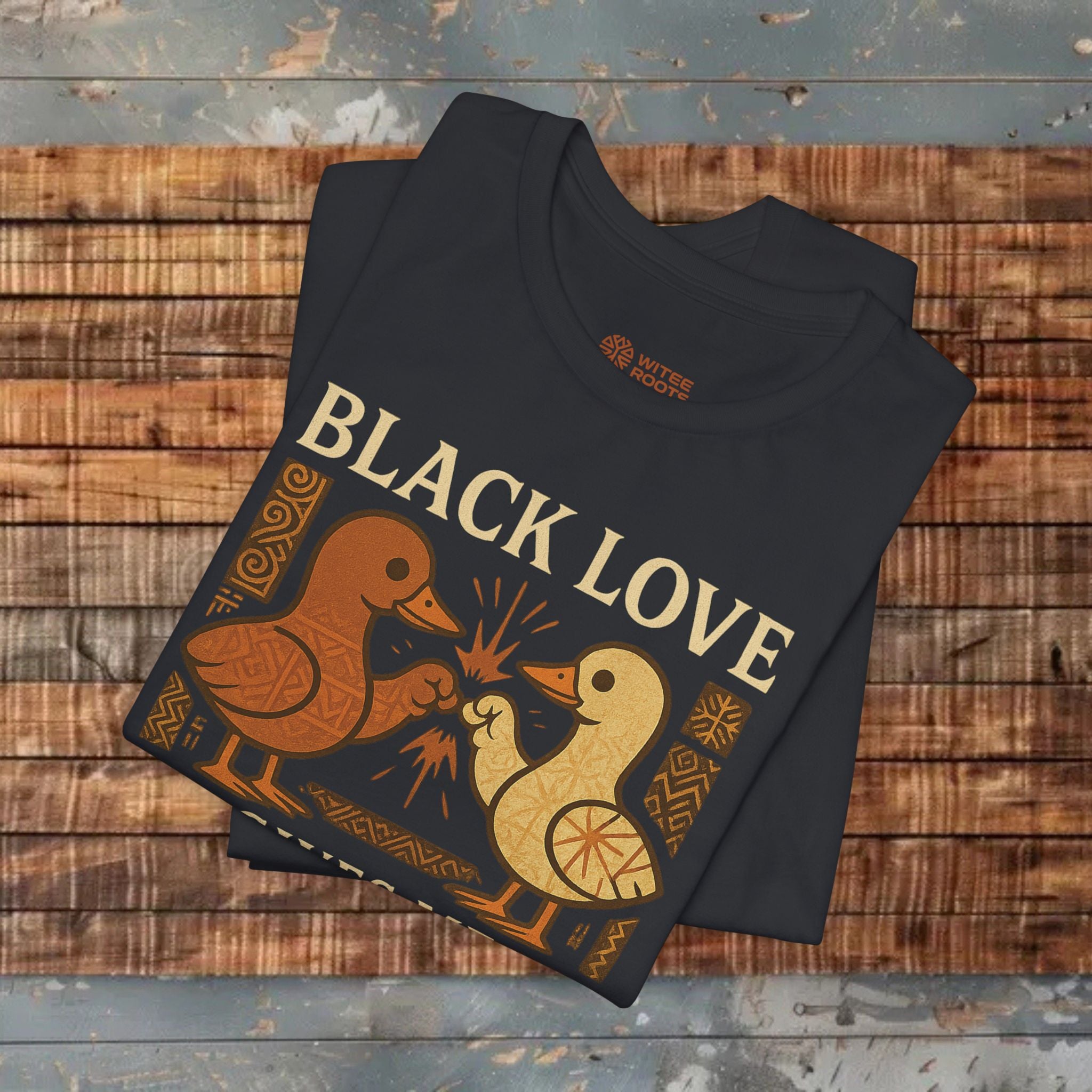 Folded black t-shirt with 'Black Love' design on a wooden surface