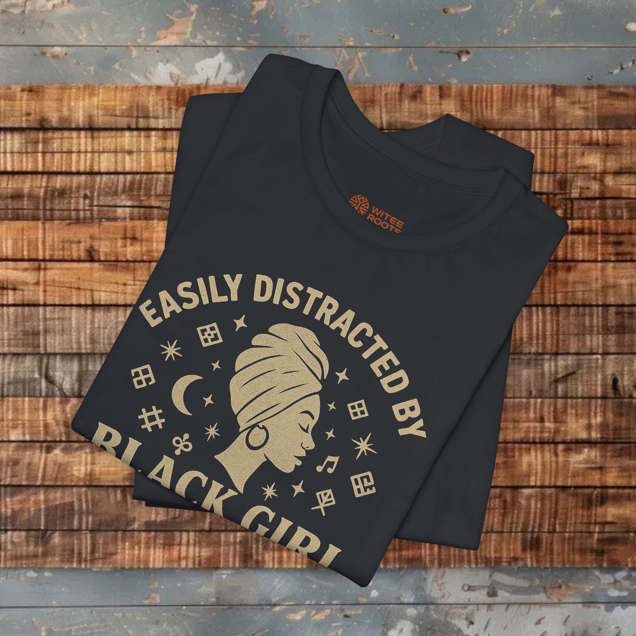 Black t-shirt with 'Easily Distracted by Black Girl' design on a wooden surface