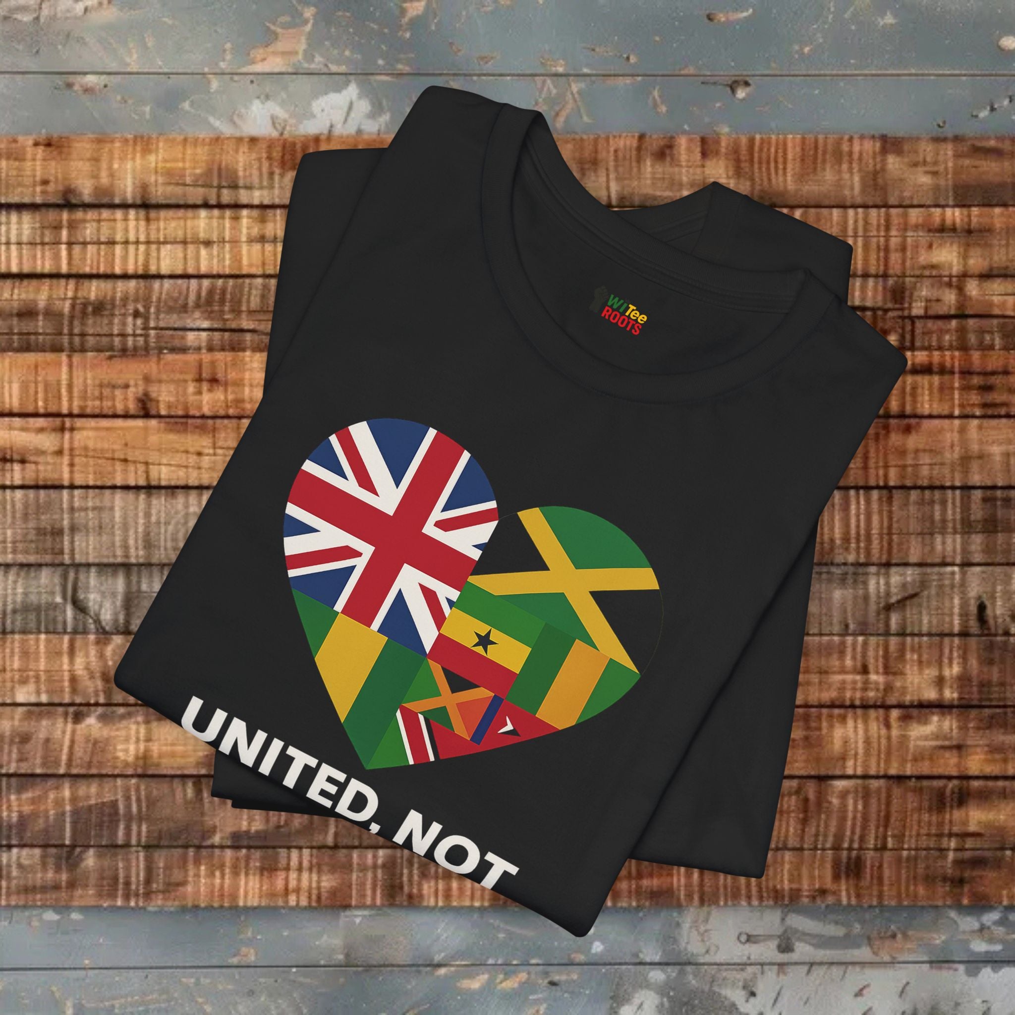 Black t-shirt with a heart design featuring multiple flags and 'UNITED. NOT' text on a wooden surface.