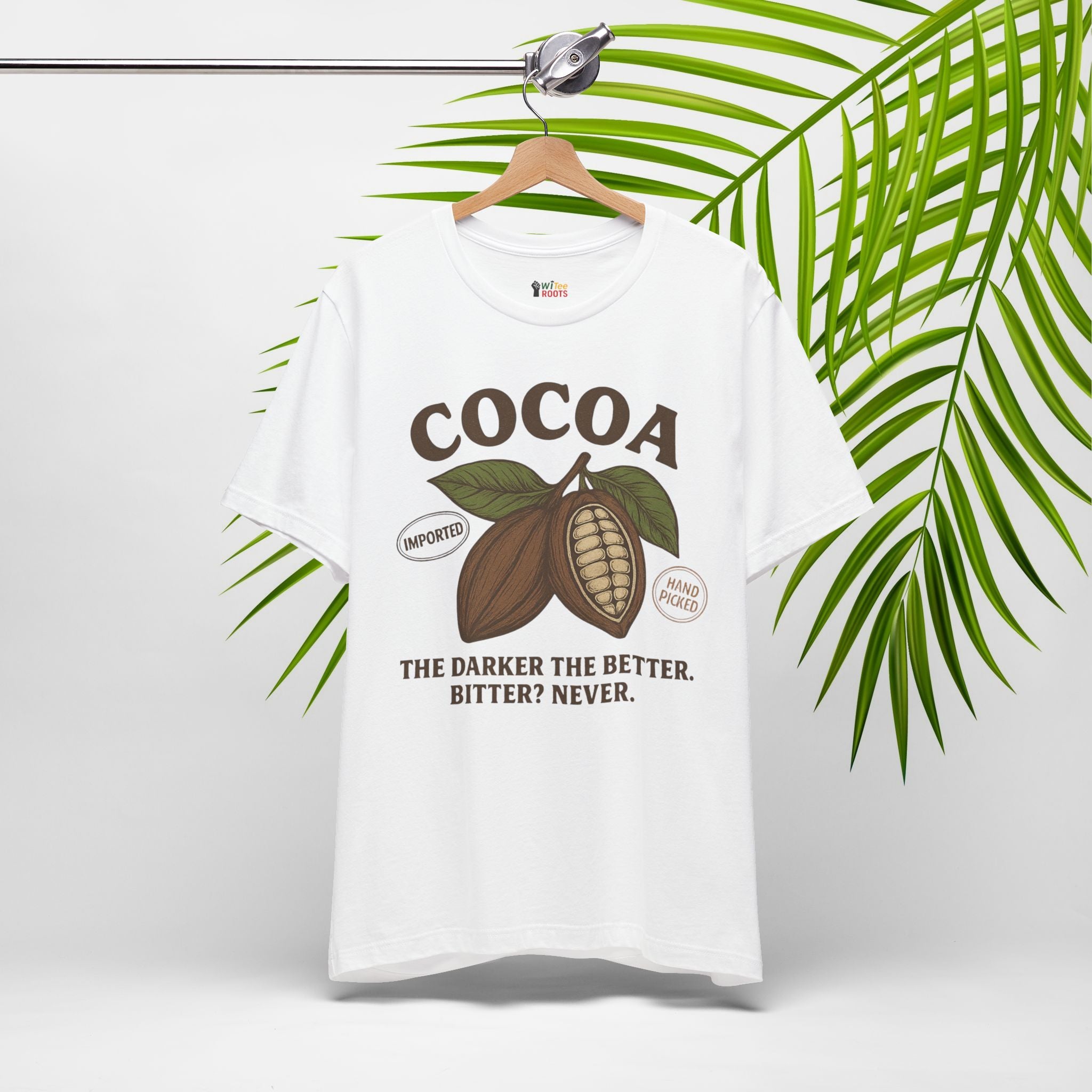 White t-shirt with cocoa graphic and text on a hanger with green leaves in the background