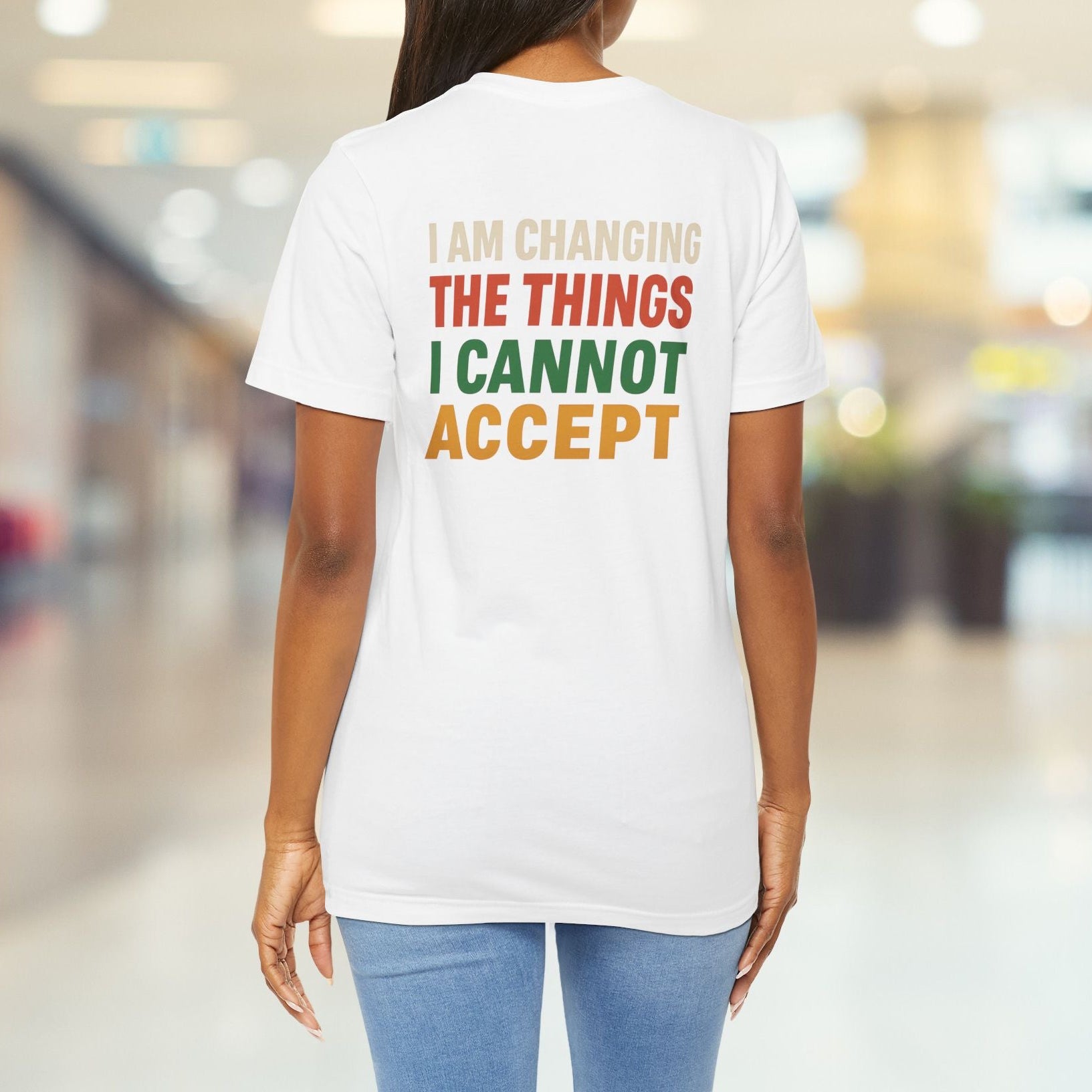 Person wearing a white t-shirt with a motivational quote in a blurred indoor setting