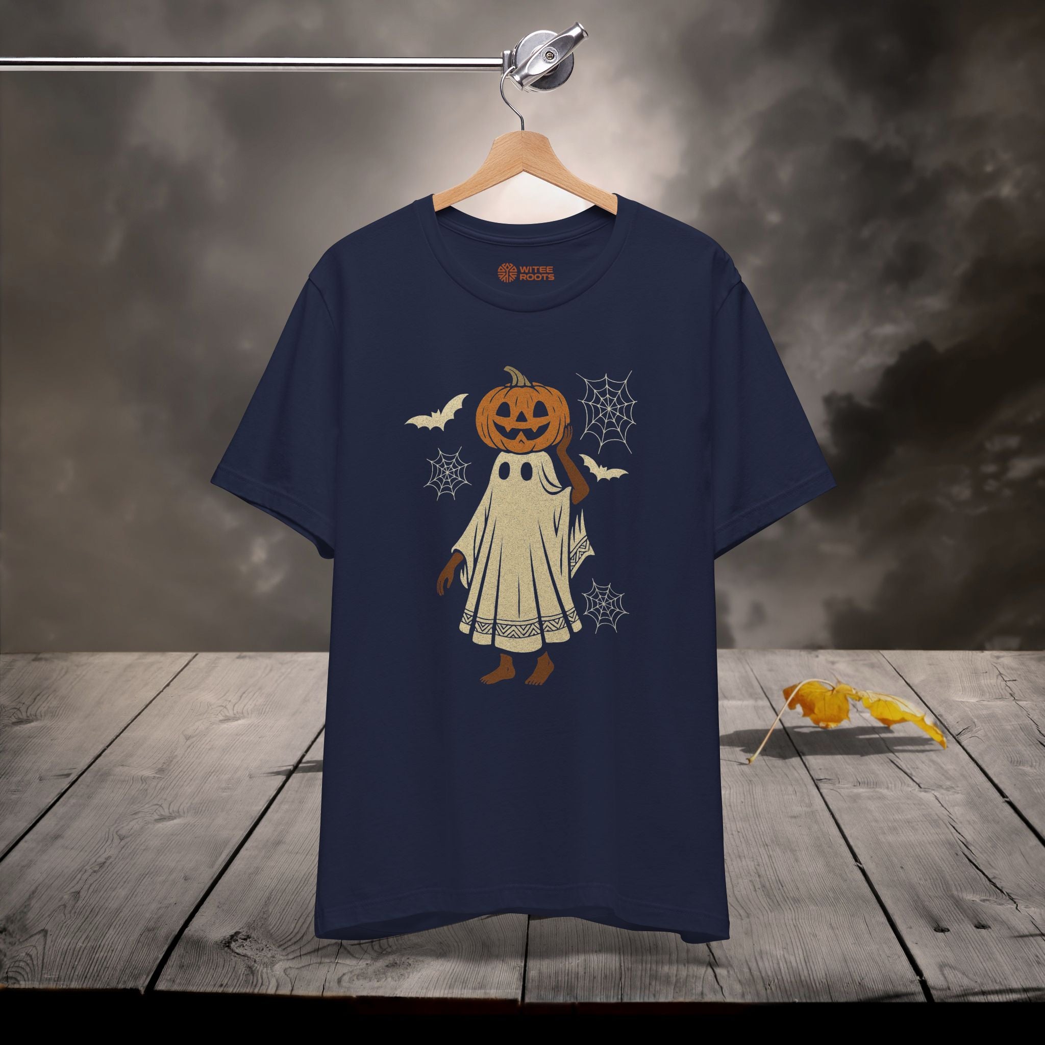 Navy blue t-shirt with Halloween-themed design on a wooden surface with a dark background