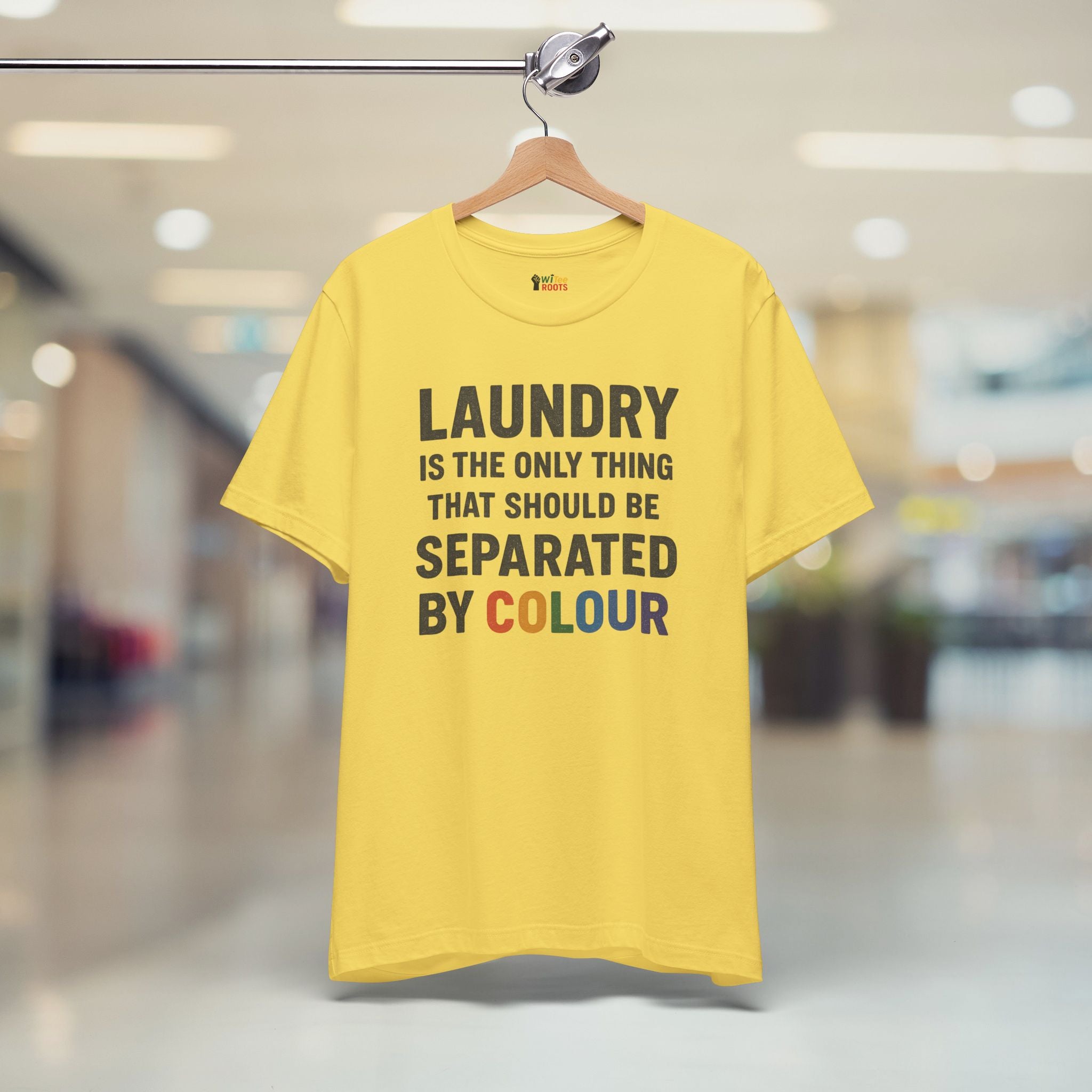 Yellow t-shirt with humorous text on a hanger in a blurred indoor setting