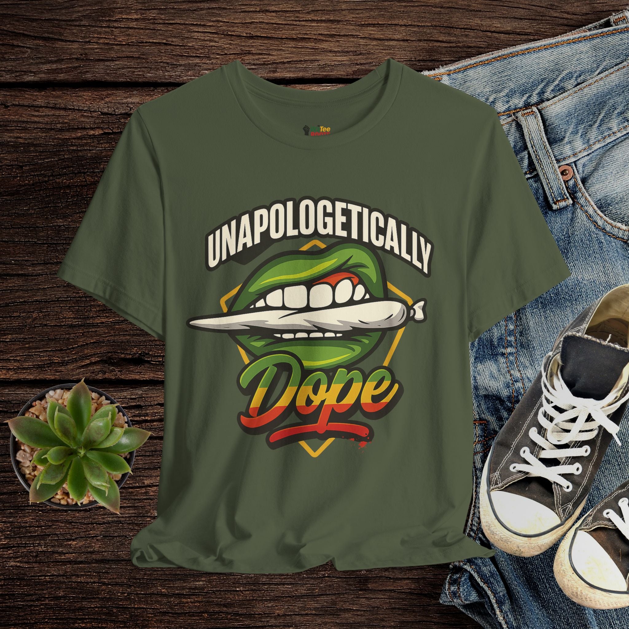 Green t-shirt with graphic design and text on a wooden surface with jeans and sneakers.