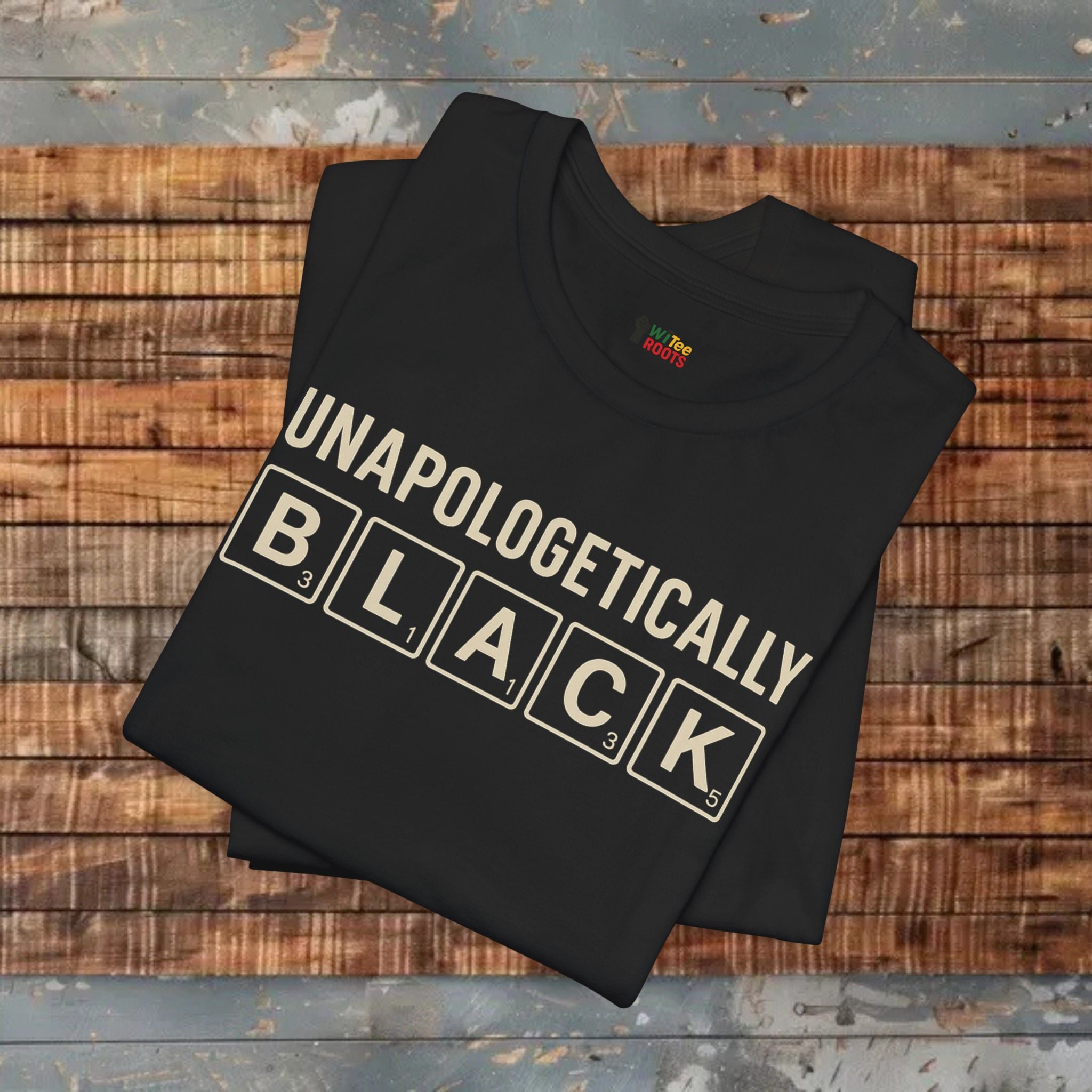Black t-shirt with 'UNAPOLOGETICALLY BLACK' text on a wooden surface