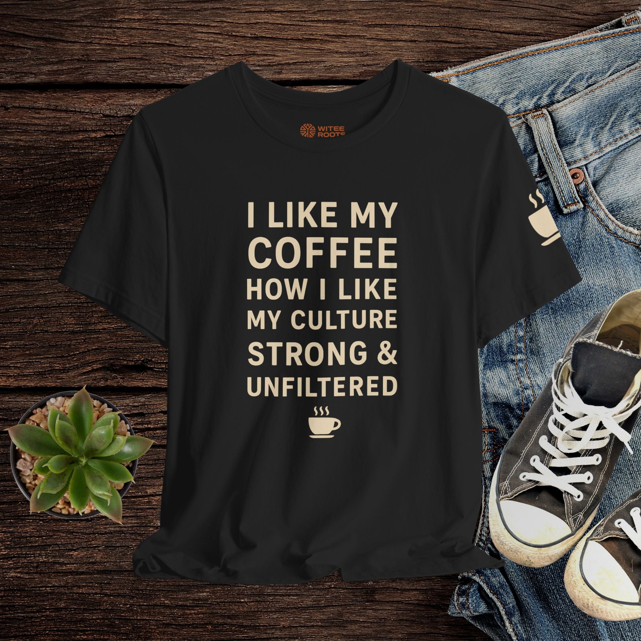 Black t-shirt with text on a wooden surface with jeans and sneakers.