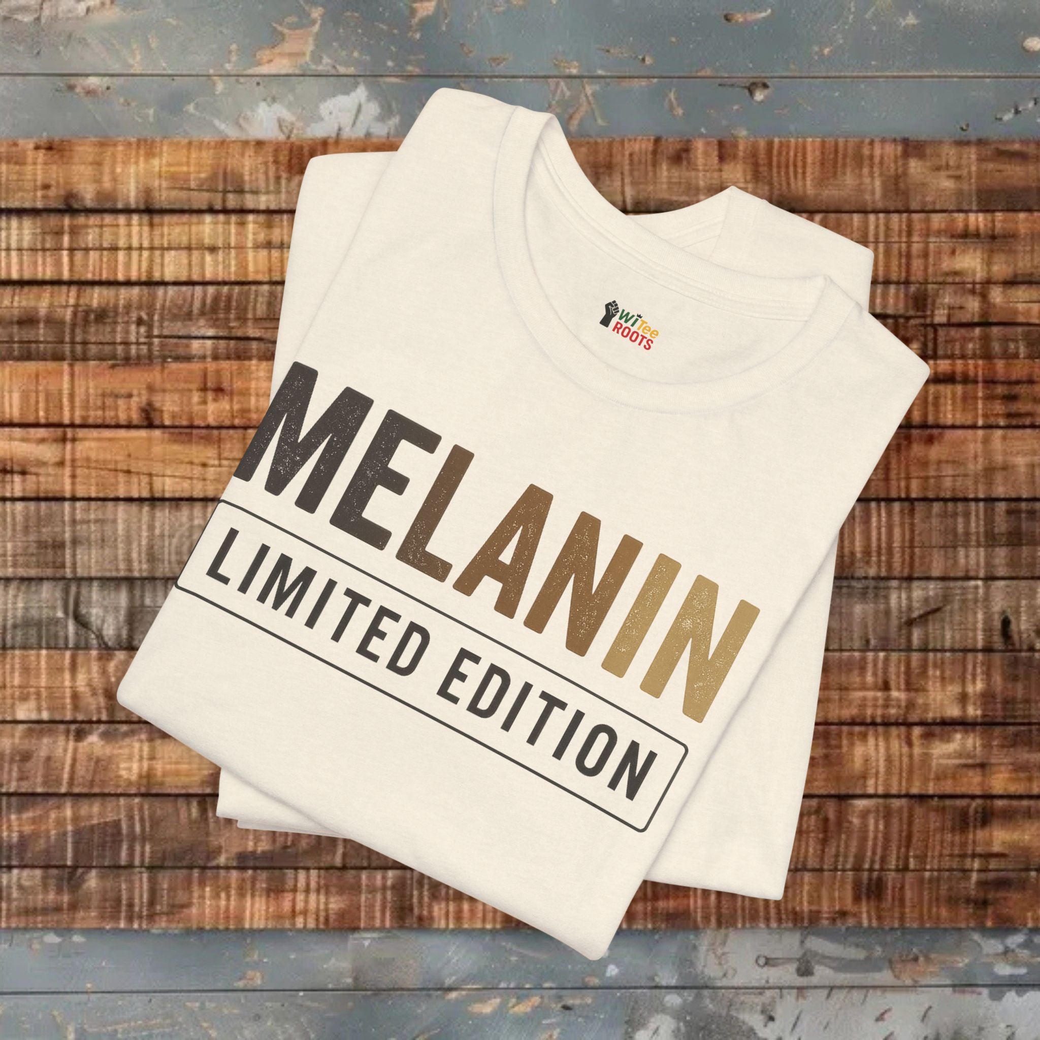 Folded t-shirt with 'Melanin Limited Edition' text on a wooden surface