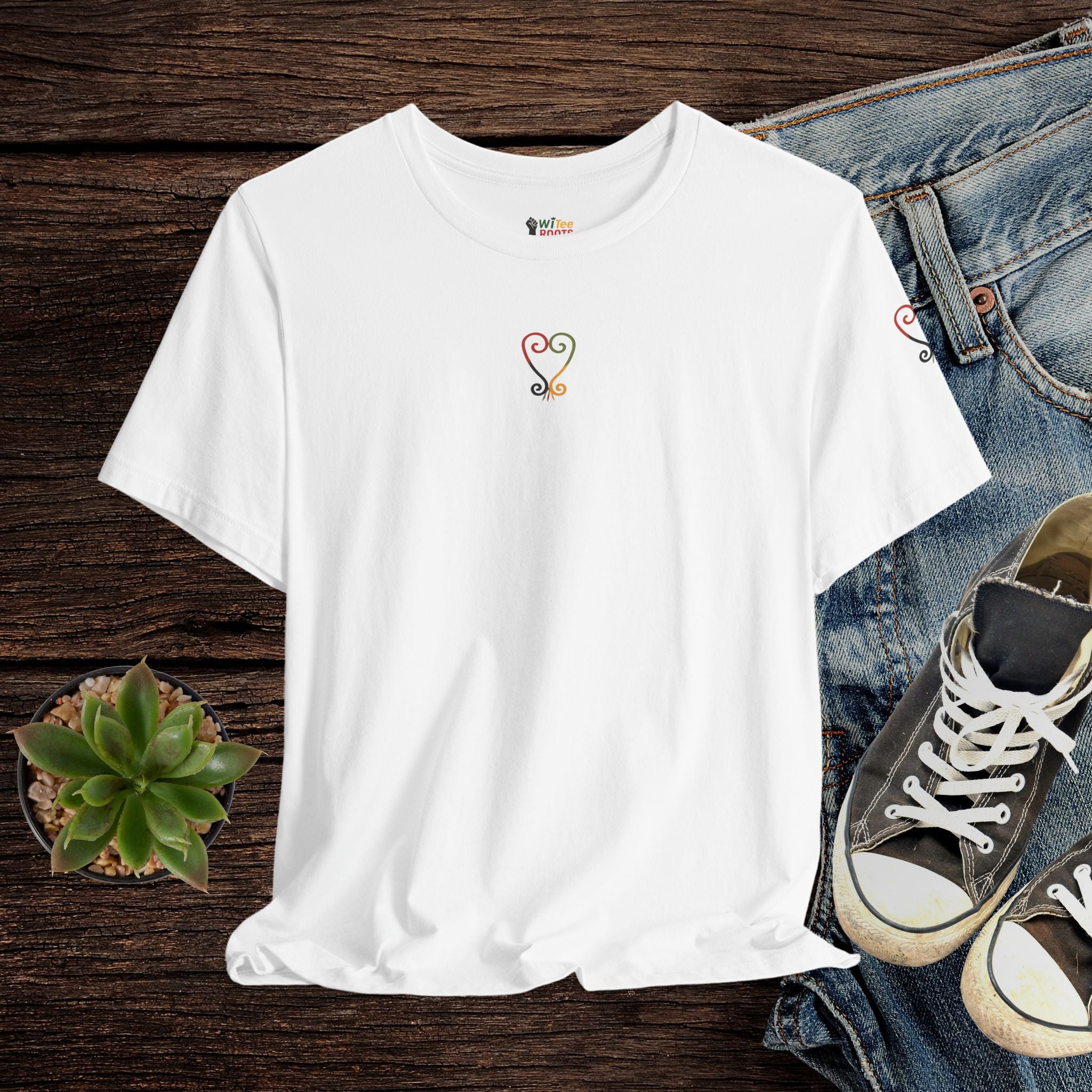 White t-shirt with a small logo on a wooden surface with jeans and sneakers.