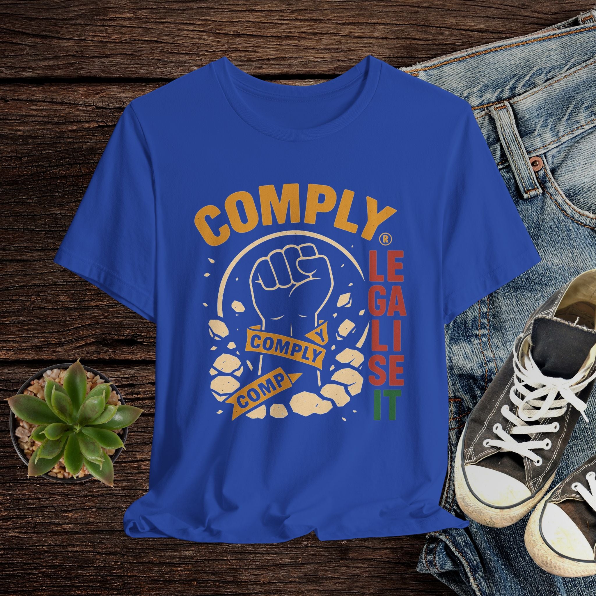 Blue t-shirt with graphic design and text on a wooden surface with jeans and sneakers.