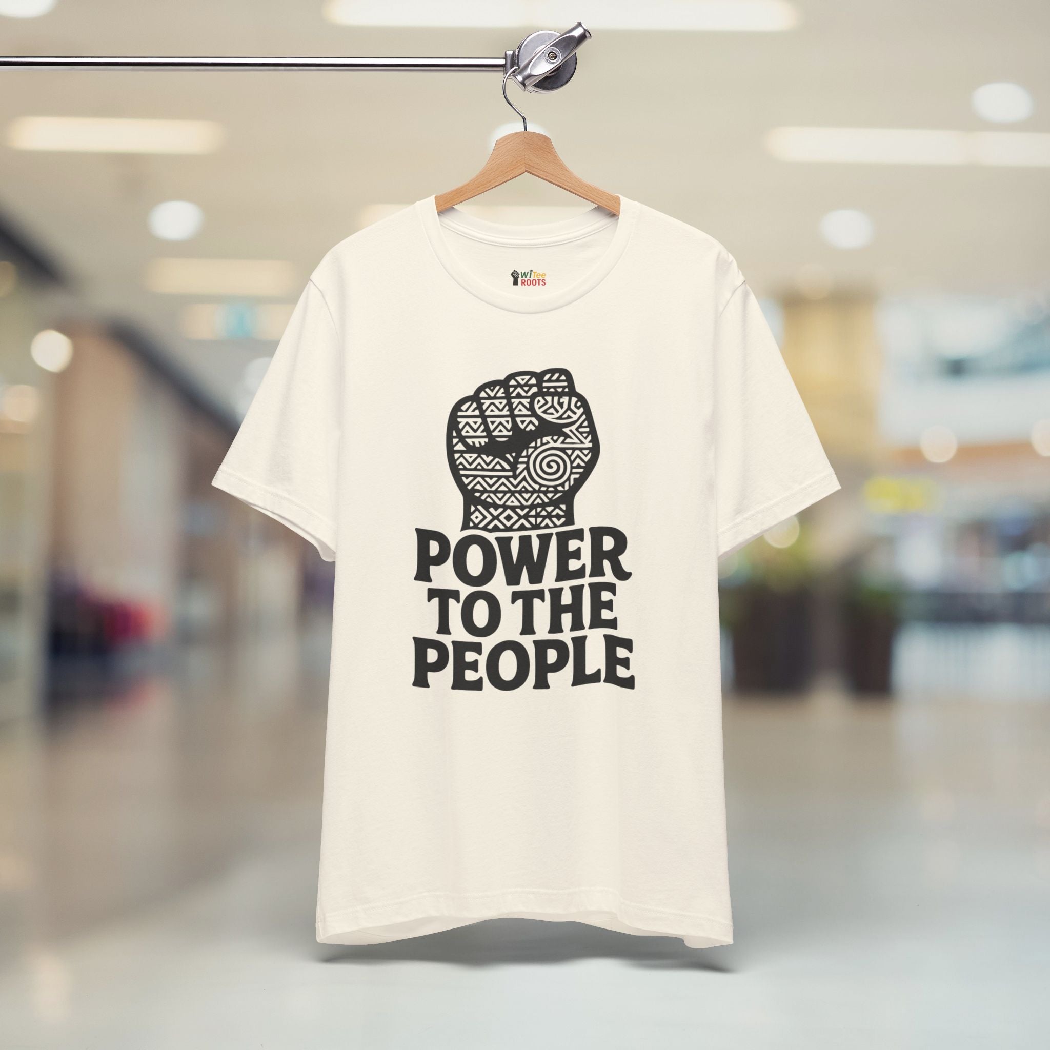 Beige t-shirt with 'Power to the People' graphic on a hanger in a store.