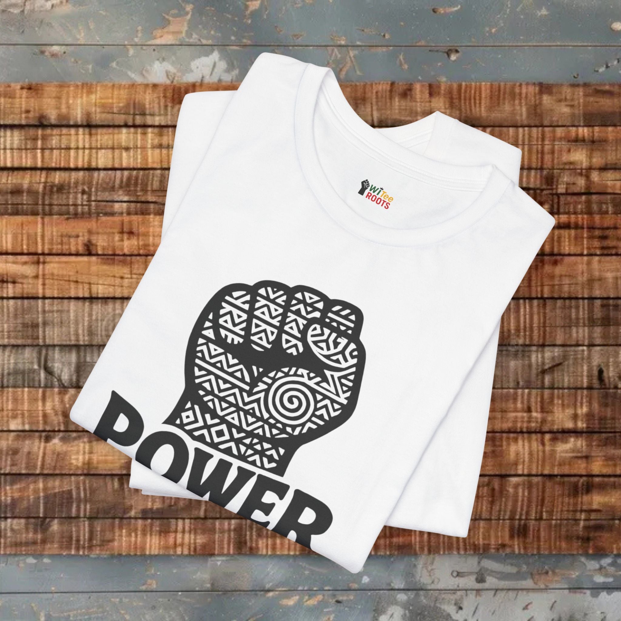 White t-shirt with a black fist graphic and 'POWER' text on a wooden surface