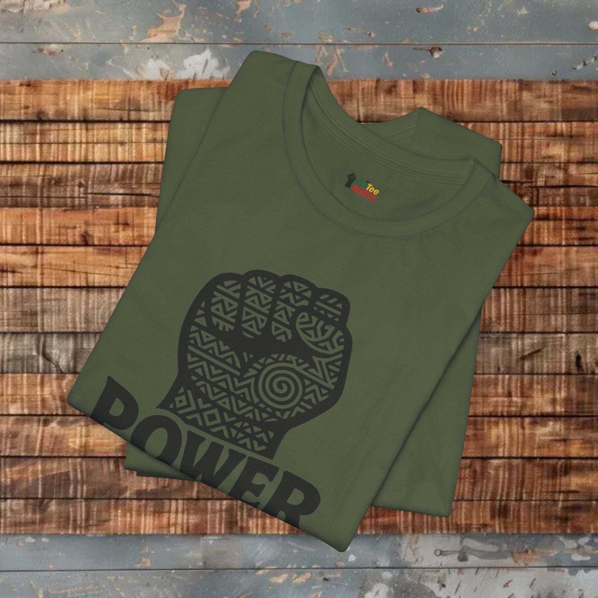 Green t-shirt with a black fist graphic and 'POWER' text on a wooden surface