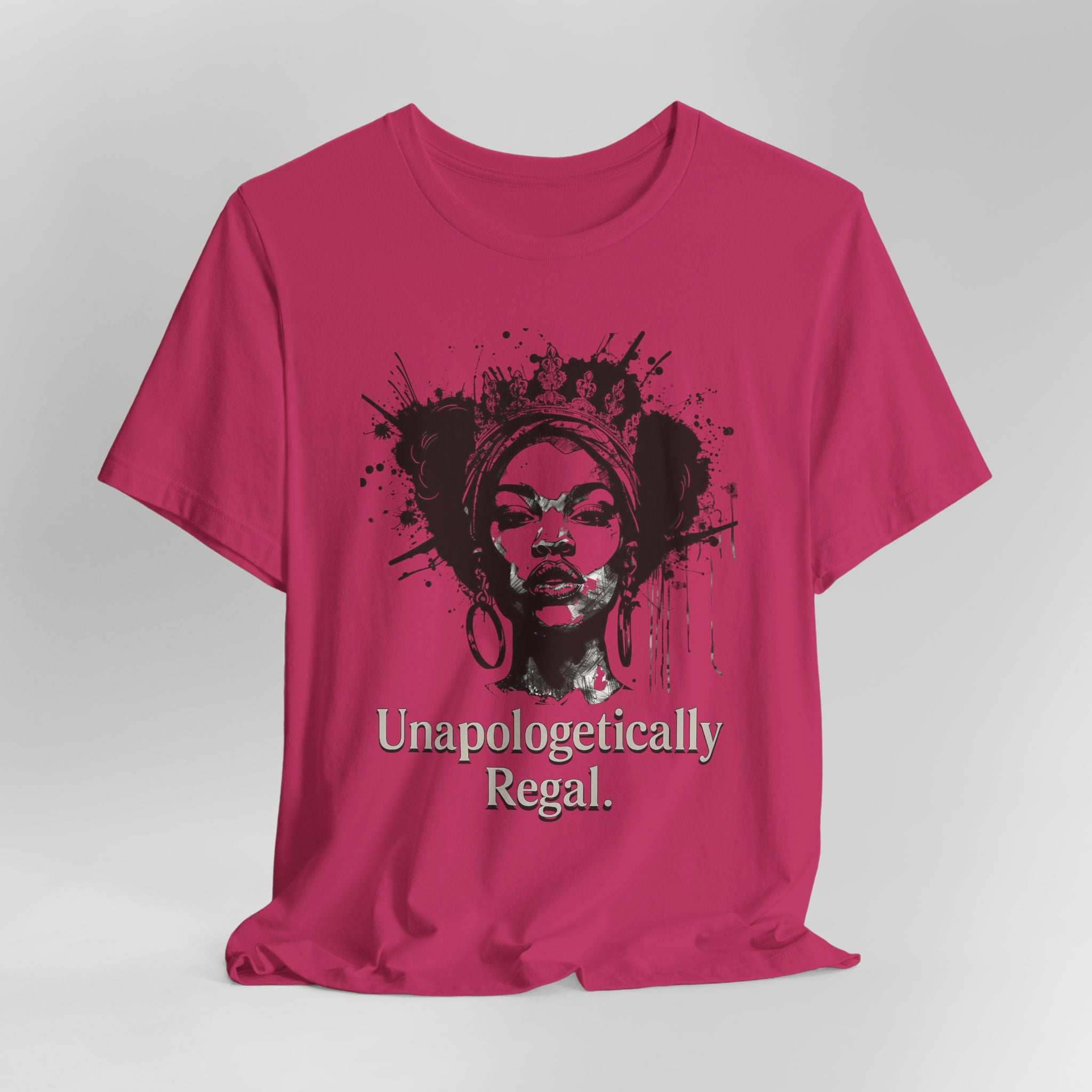 Pink t-shirt with a graphic of a woman's face and the text 'Unapologetically Regal' on a gray background