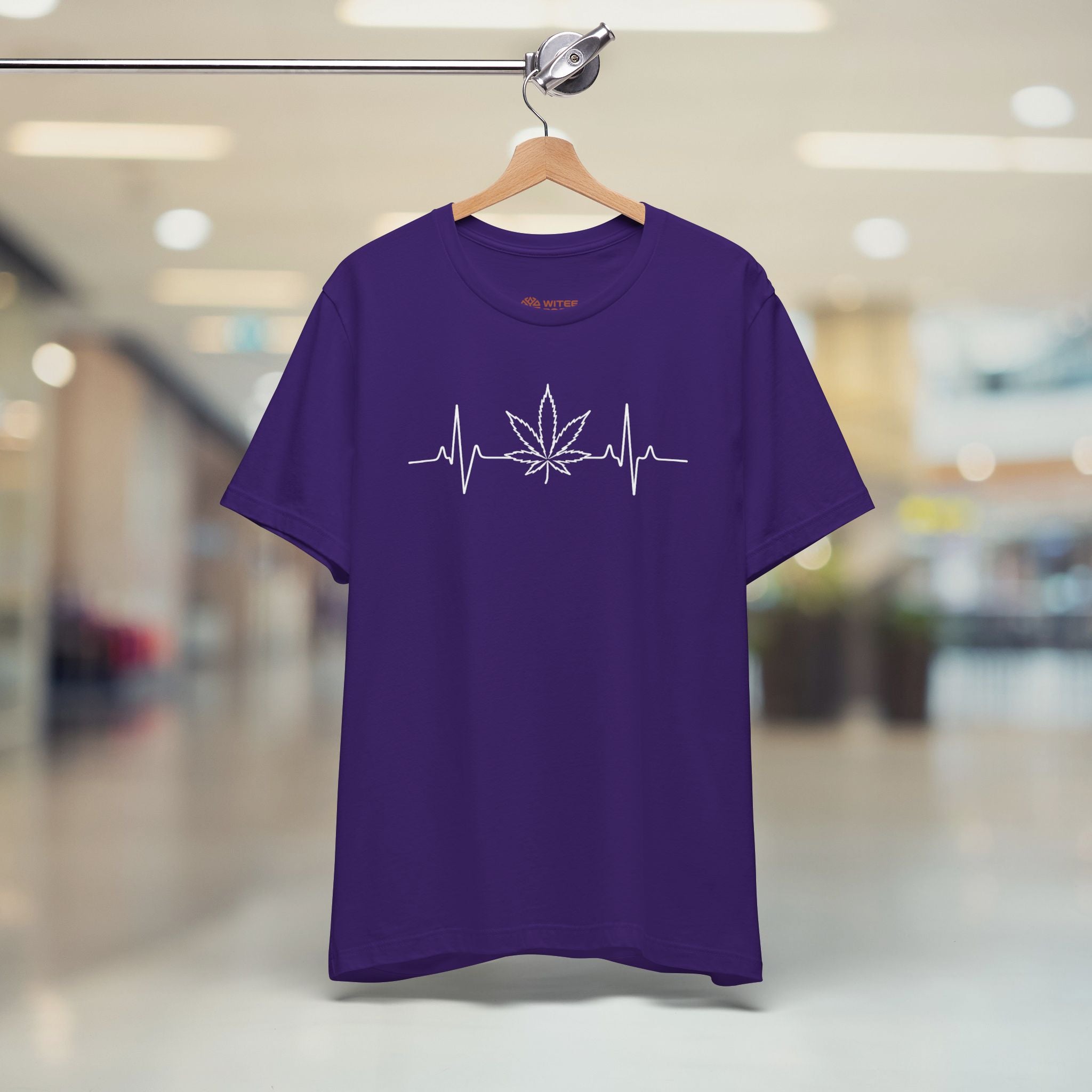 Purple t-shirt with a cannabis leaf design on a hanger in a store setting