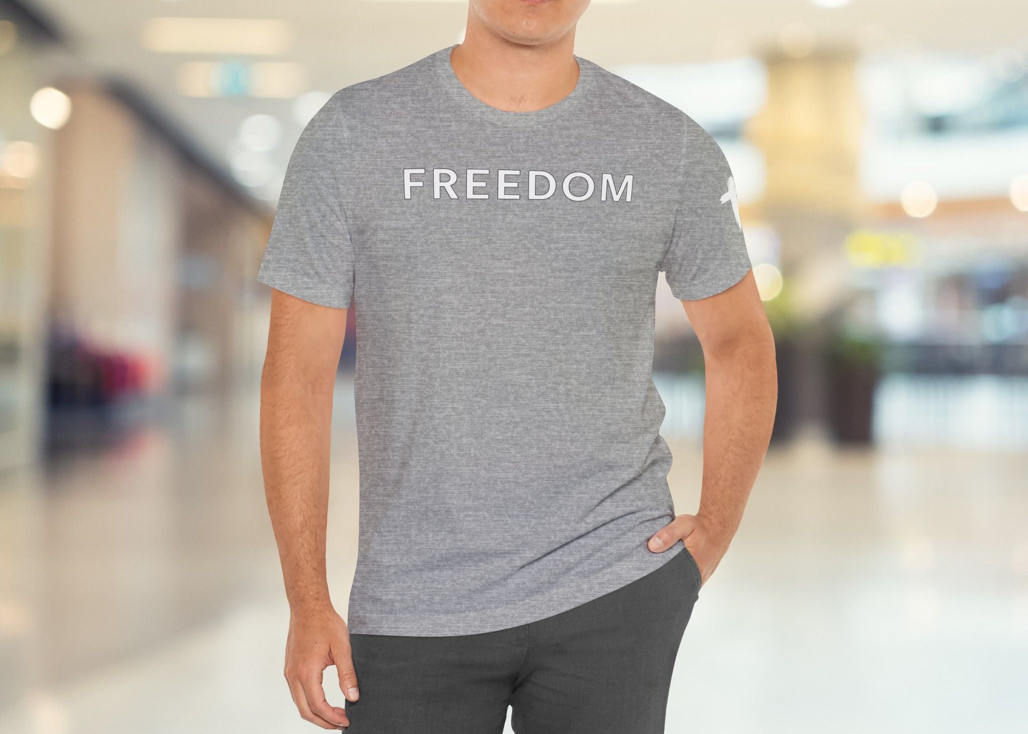 Man wearing a gray t-shirt with 'FREEDOM' text in a blurred indoor setting