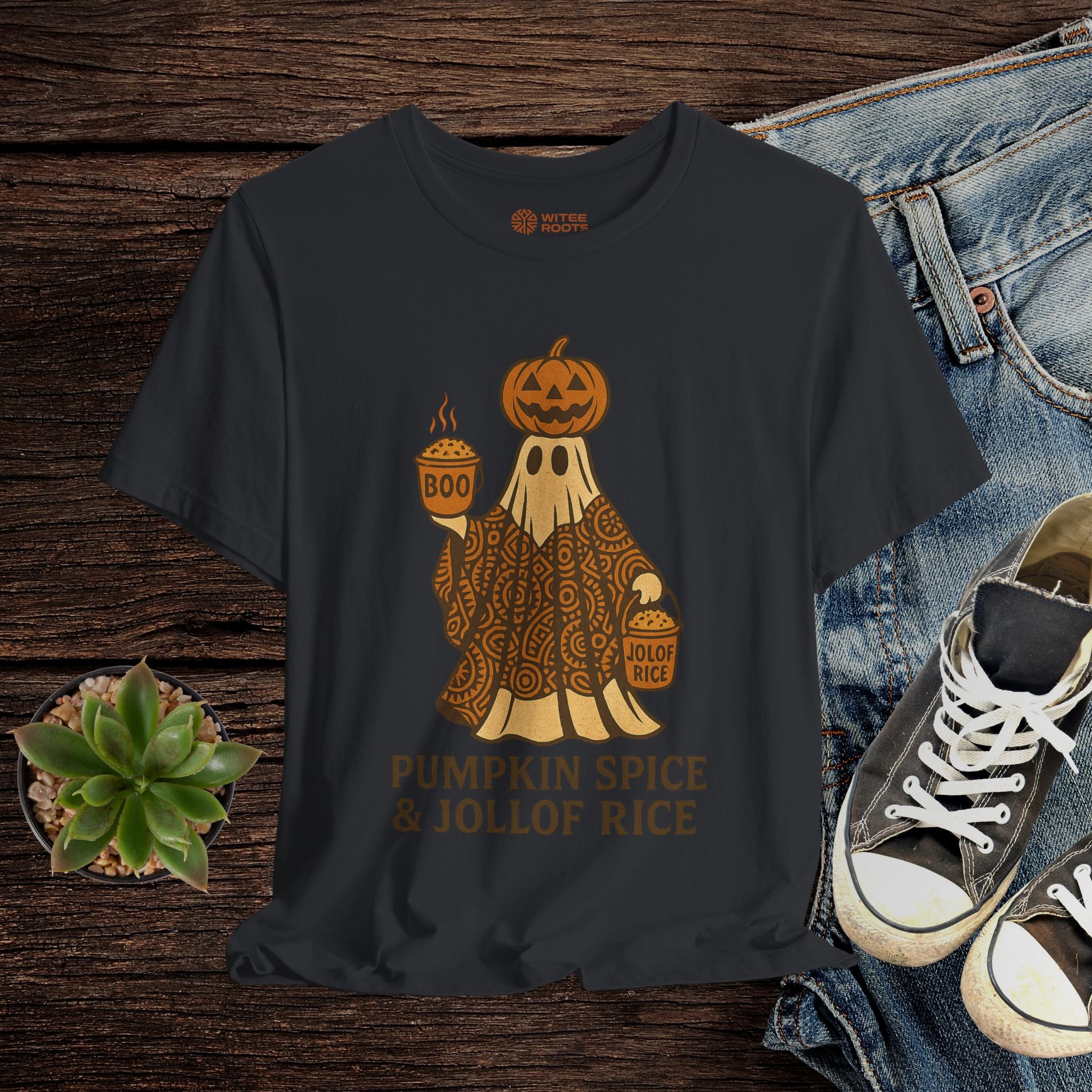 Black t-shirt with a ghost holding pumpkins and text on a wooden surface with jeans and sneakers.