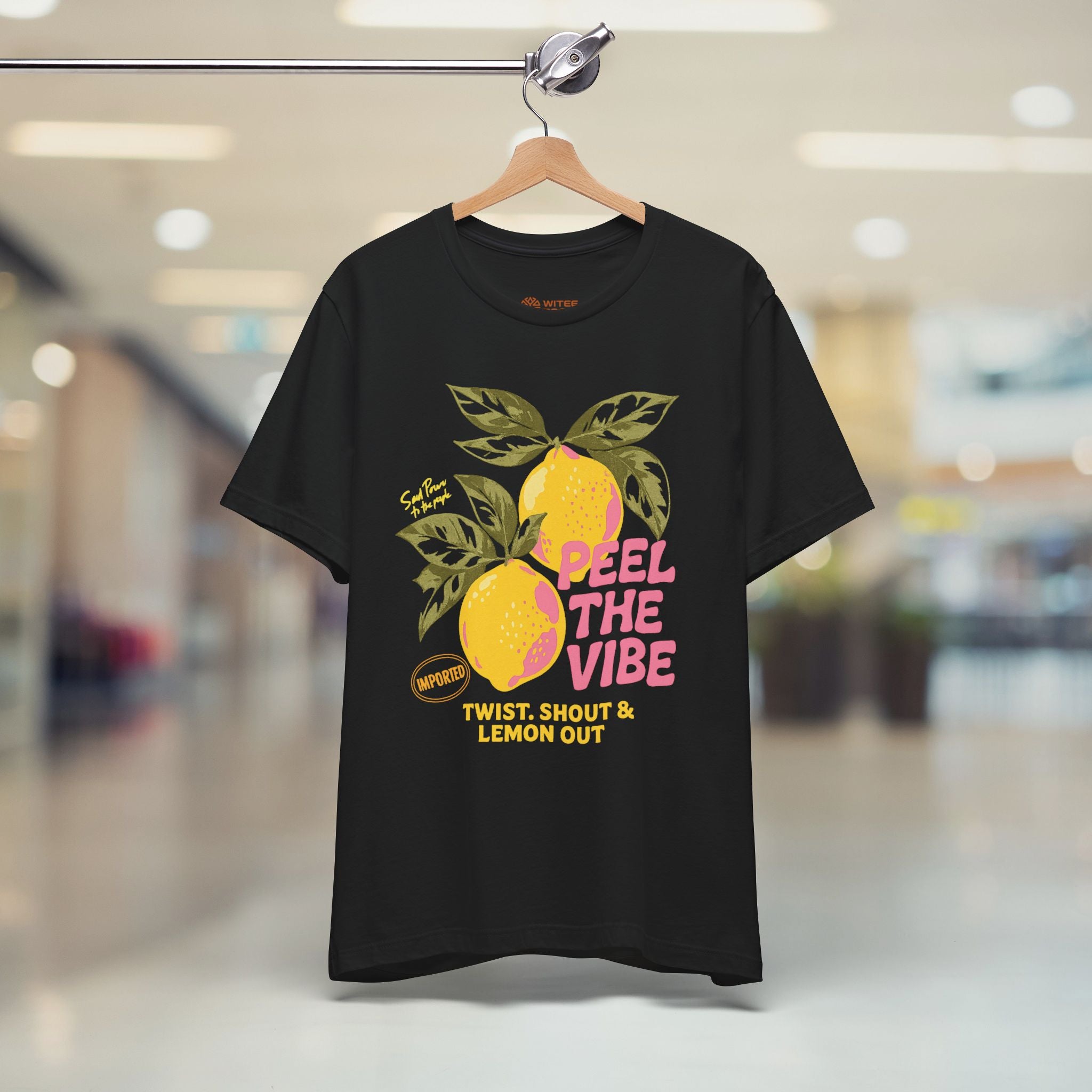 Black t-shirt with lemon graphic and text on a hanger in a store.