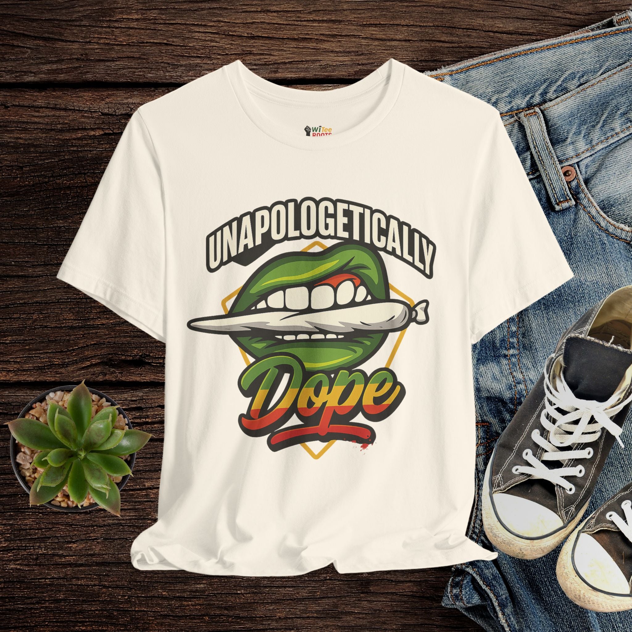 Beige t-shirt with graphic design and text on a wooden surface with jeans and sneakers.