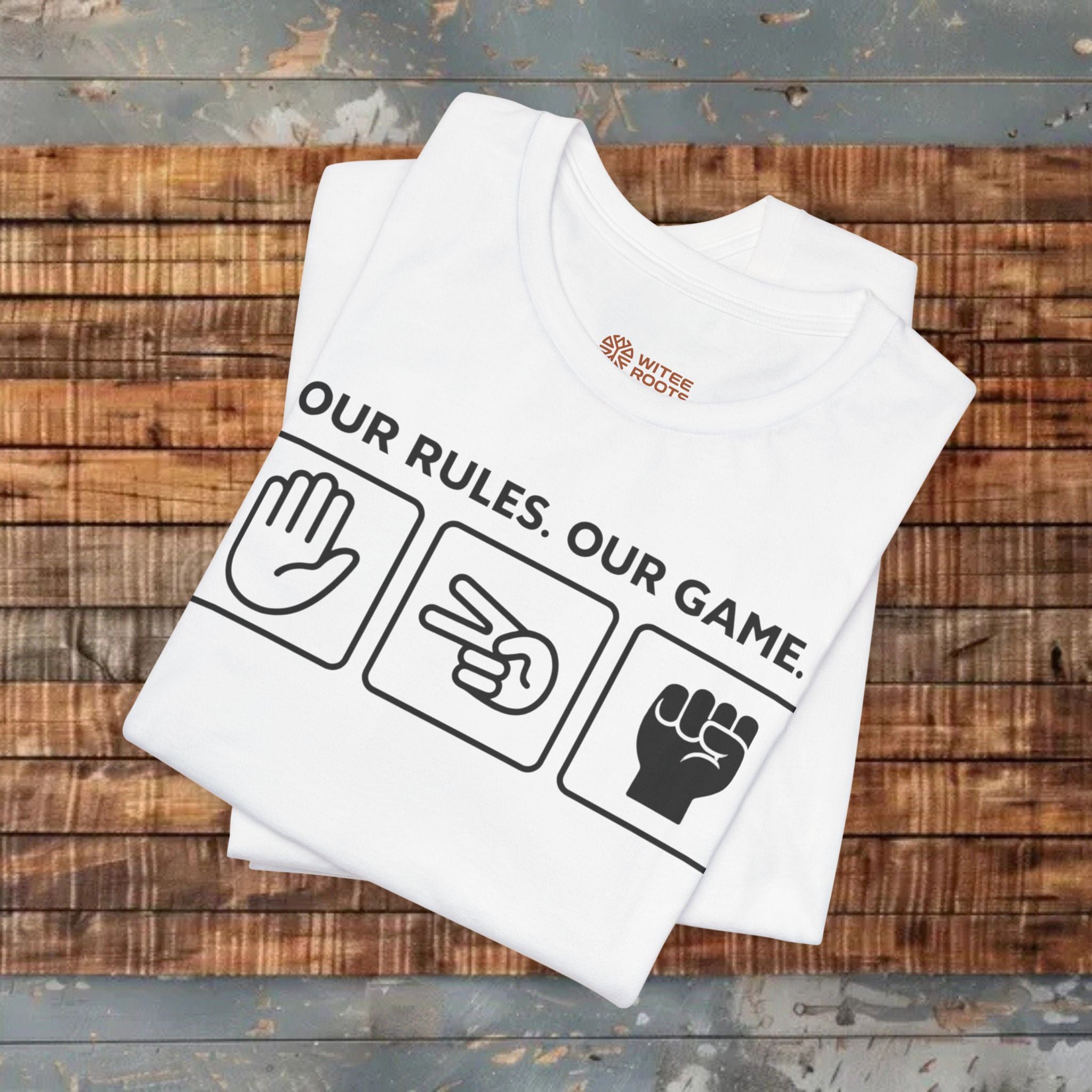 White t-shirt with 'Our Rules. Our Game.' text and graphics on a wooden surface