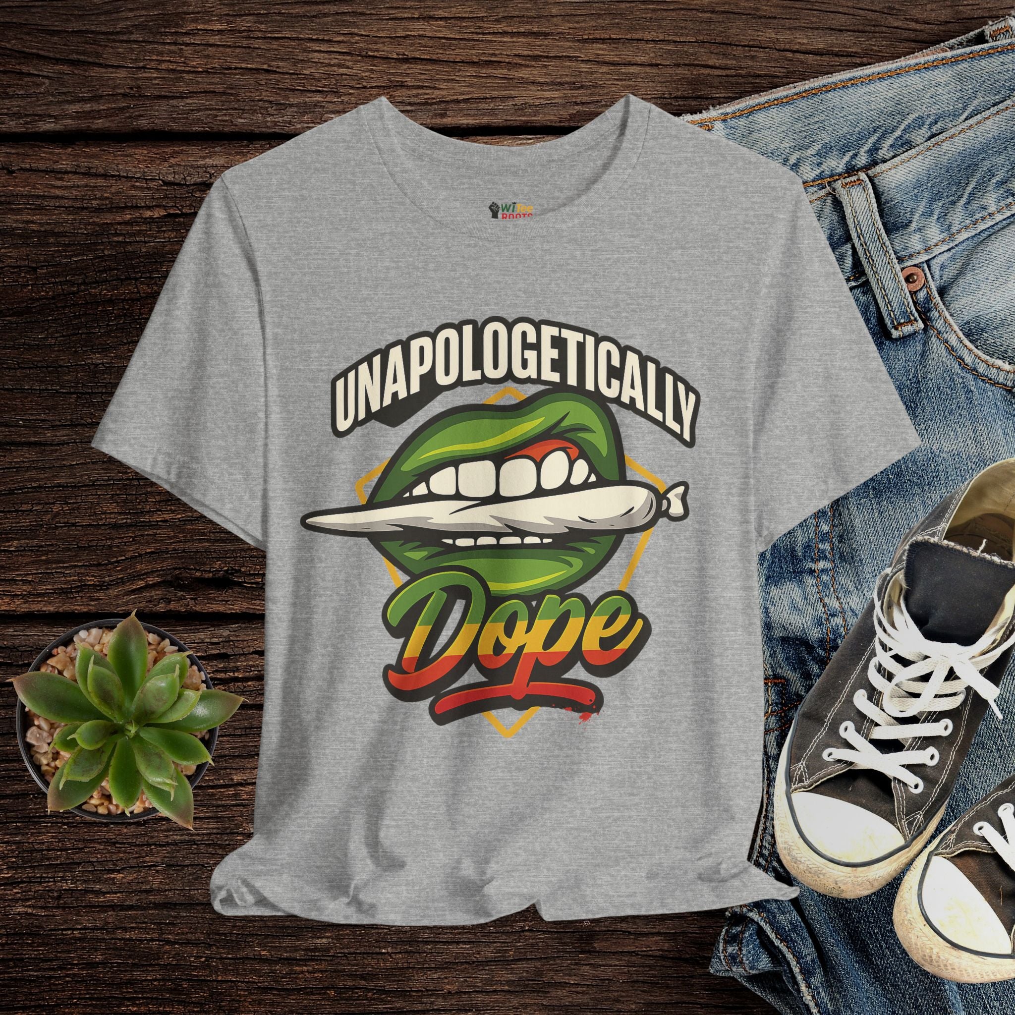 Grey t-shirt with graphic design and text on a wooden surface with jeans and sneakers.