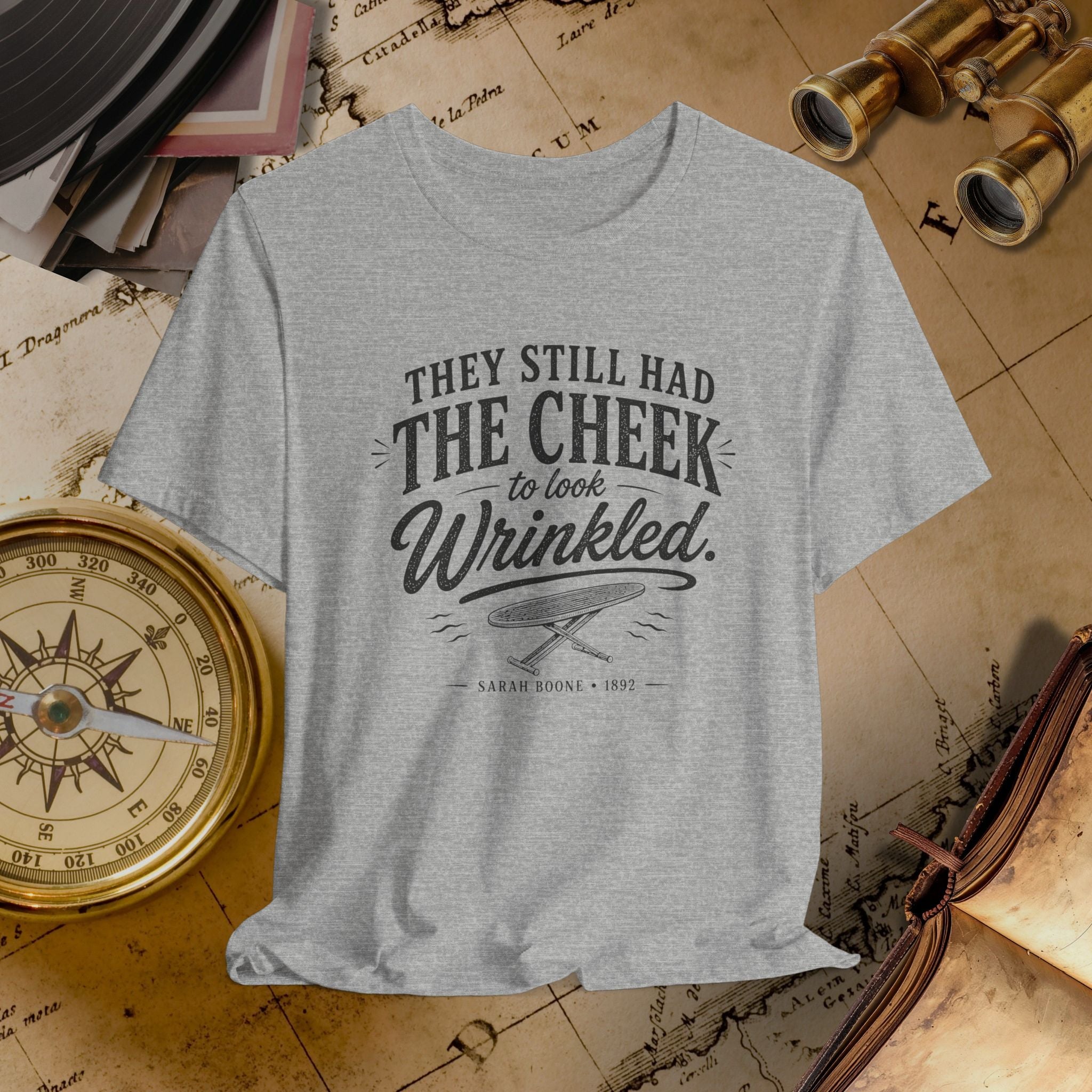 Gray t-shirt with text on a vintage background with books and binoculars.