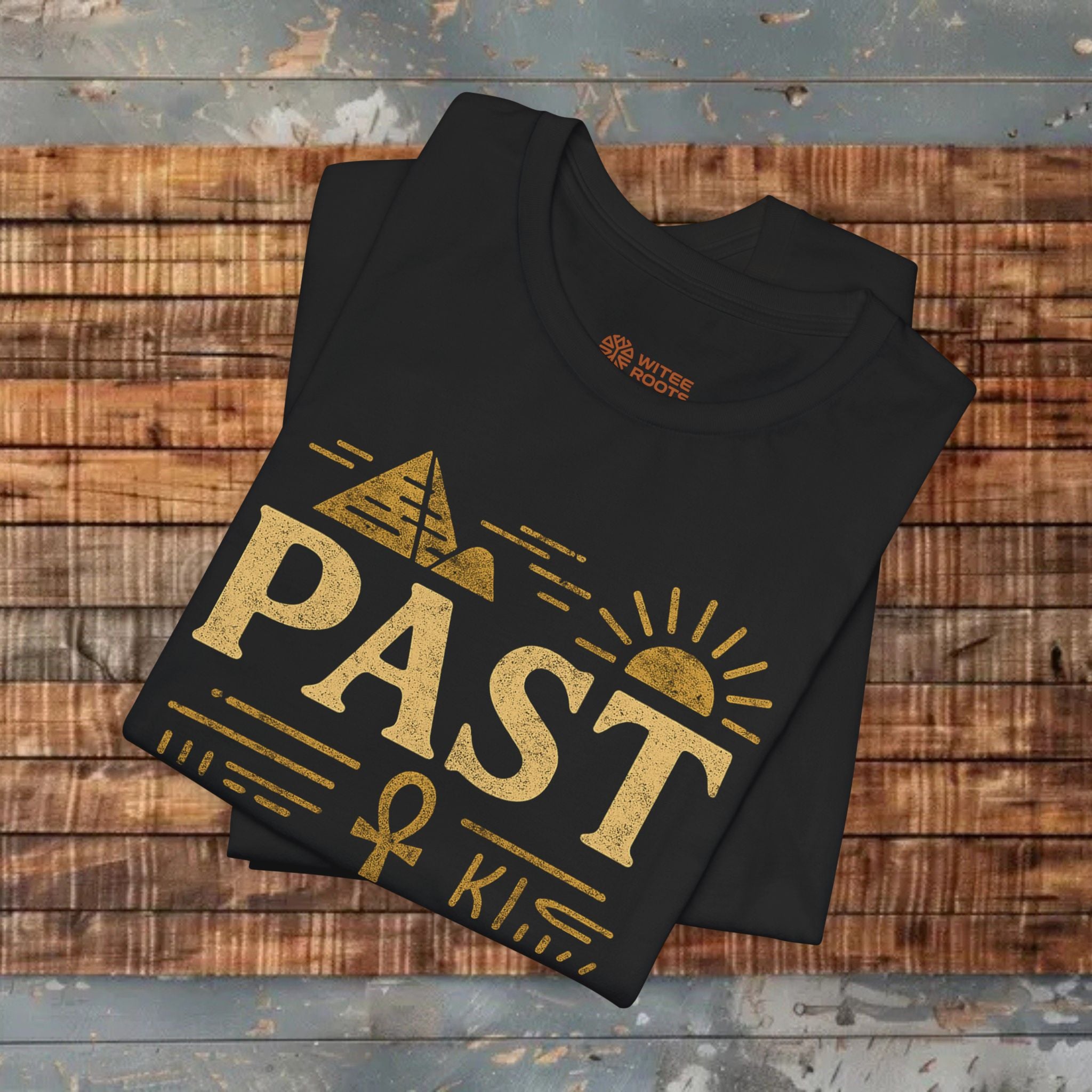 Black t-shirt with gold graphic design on a wooden surface