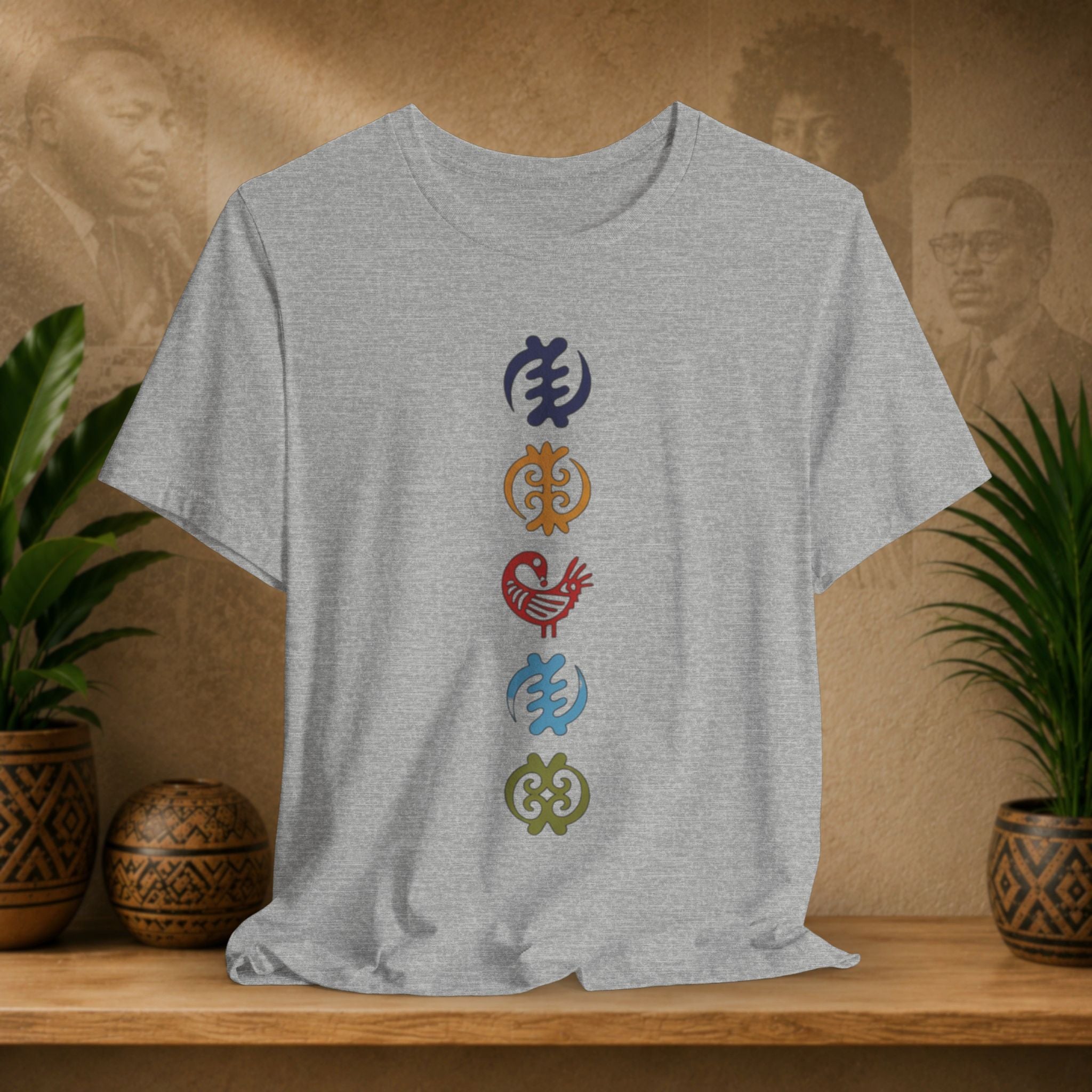 Gray t-shirt with colorful symbols on a wooden shelf with plants and decorative items.