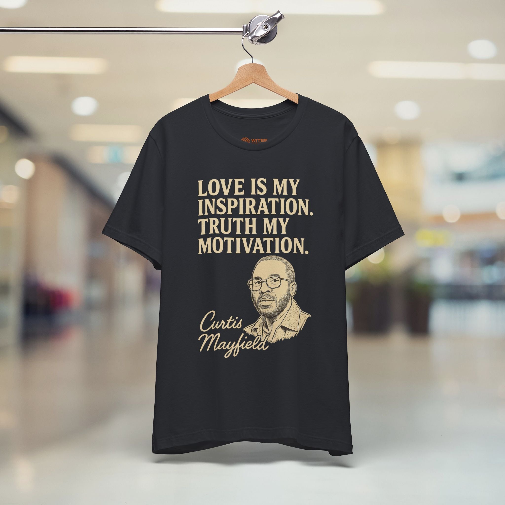 Black t-shirt with text and a portrait of Curtis Mayfield on a hanger in a store.
