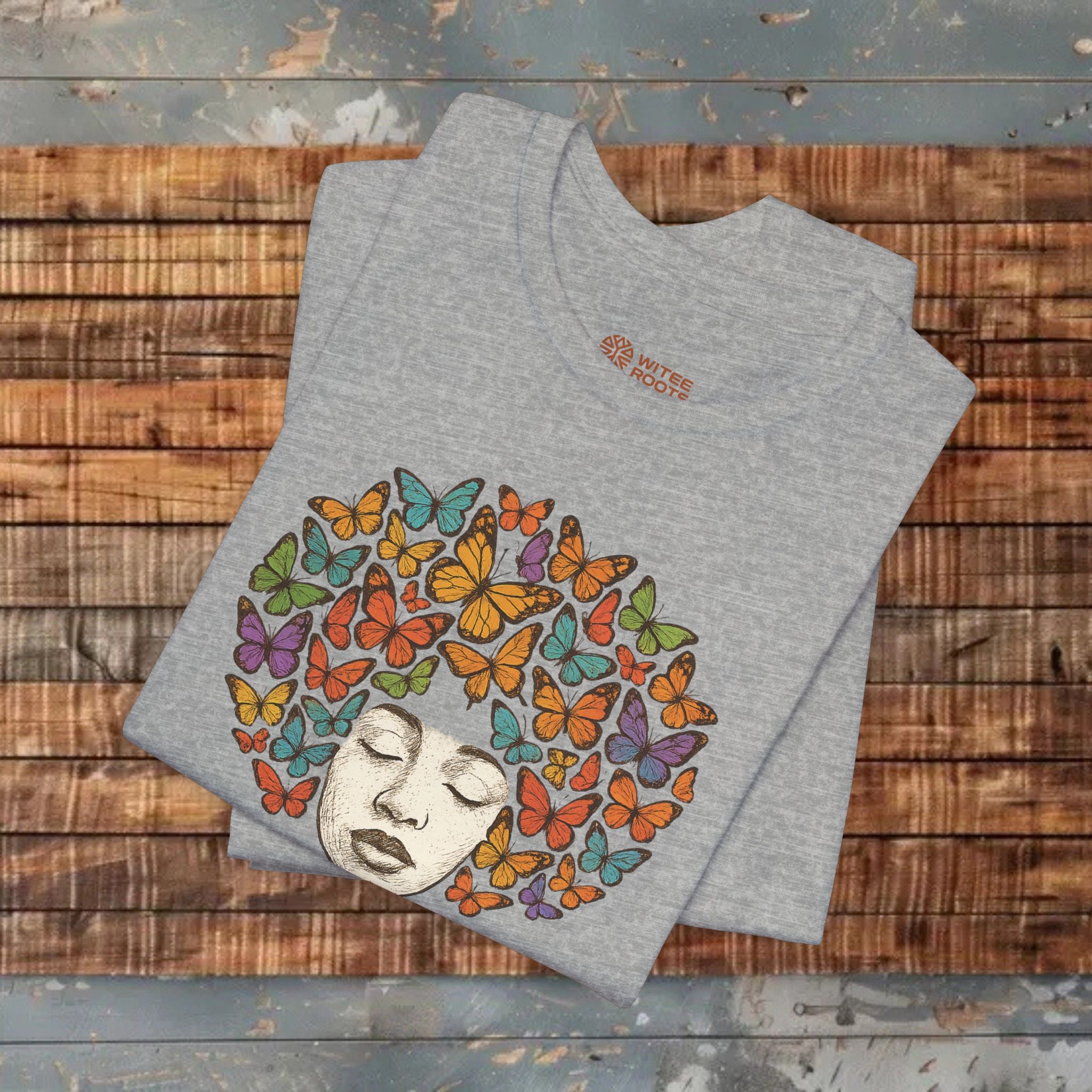 Gray t-shirt with butterfly design on a wooden surface