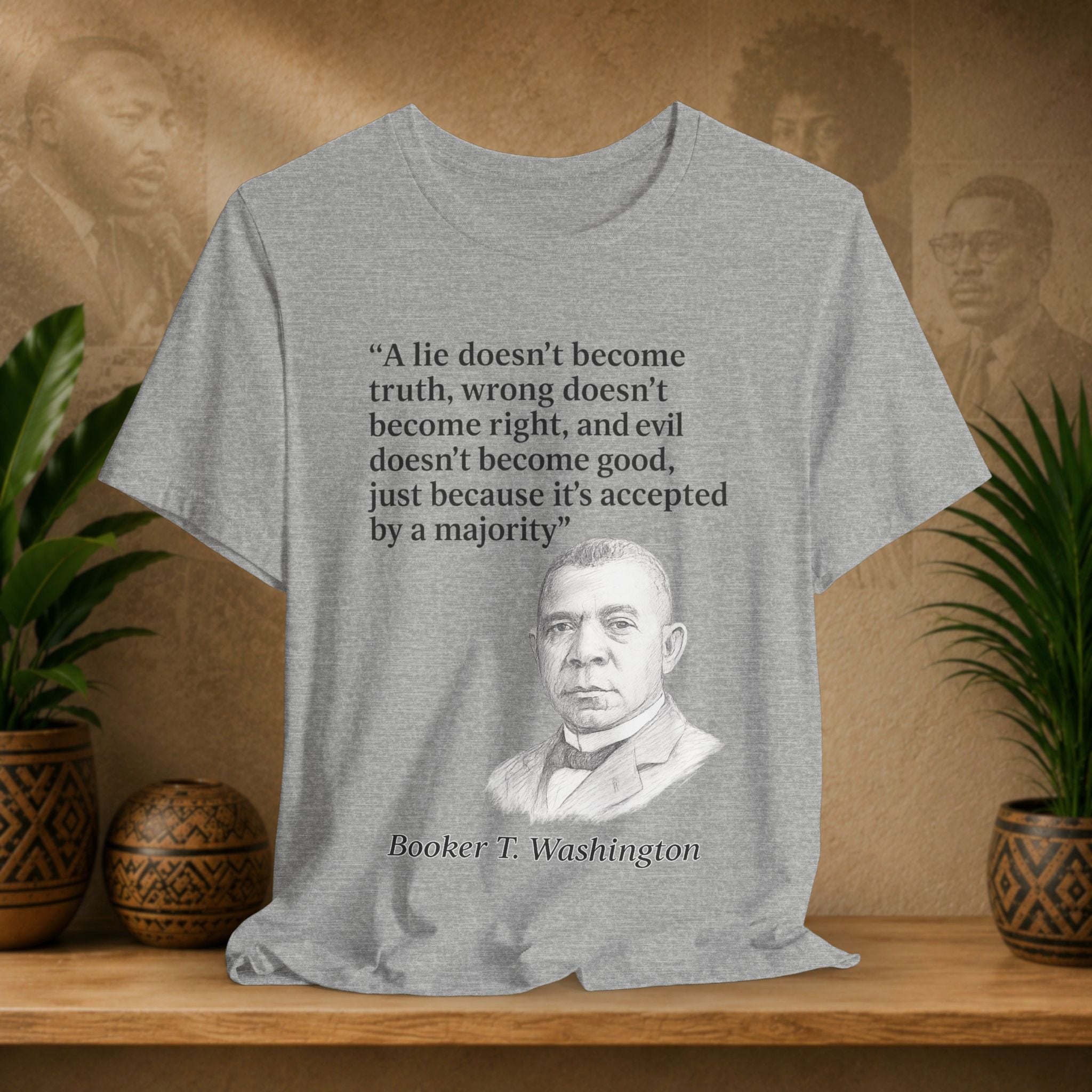 Gray t-shirt with Booker T. Washington's quote on a wooden shelf with plants and decorative items.