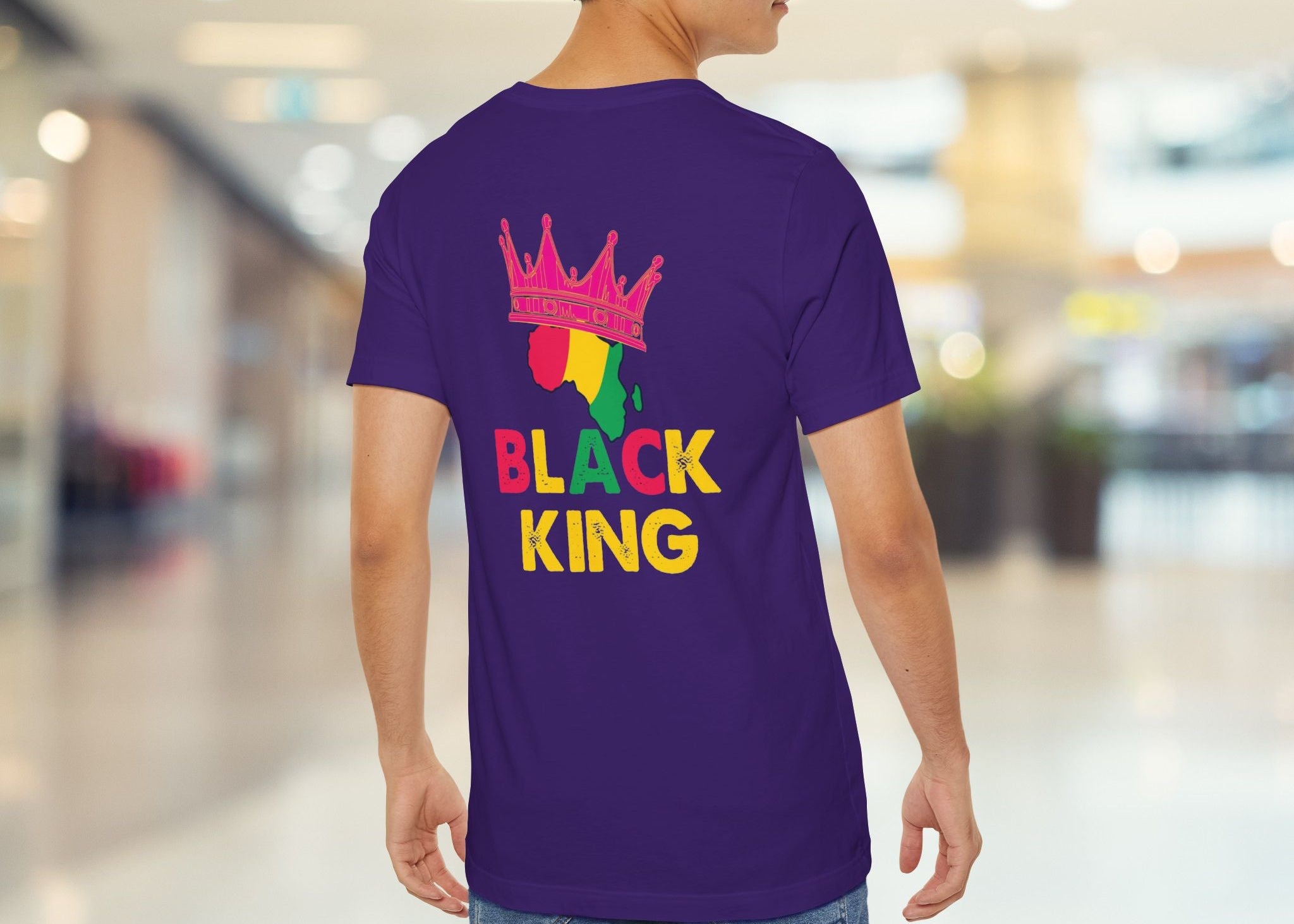 Person wearing a purple t-shirt with 'Black King' text and colorful design in a mall setting